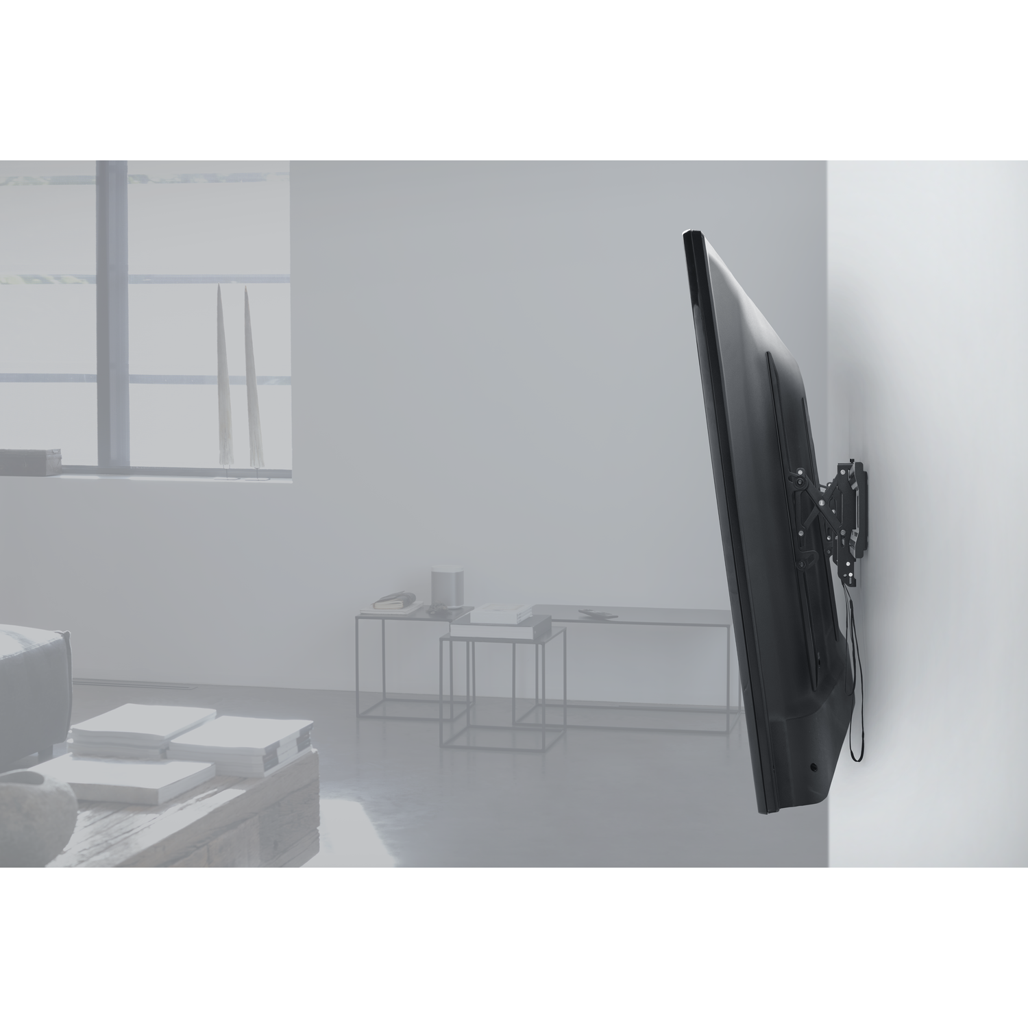 Tv gemonteerd op een witte muur. Zwart scherm, zwarte houder en kabels zichtbaar, interieur.