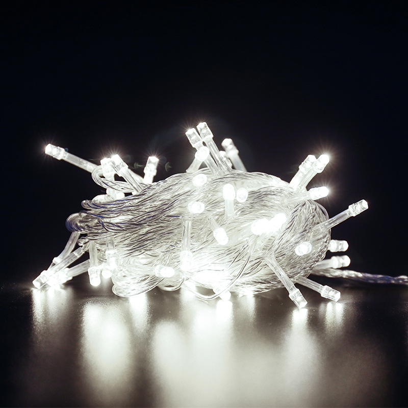 Białe lampki choinkowe na stole, podświetlane na ciemnym tle.