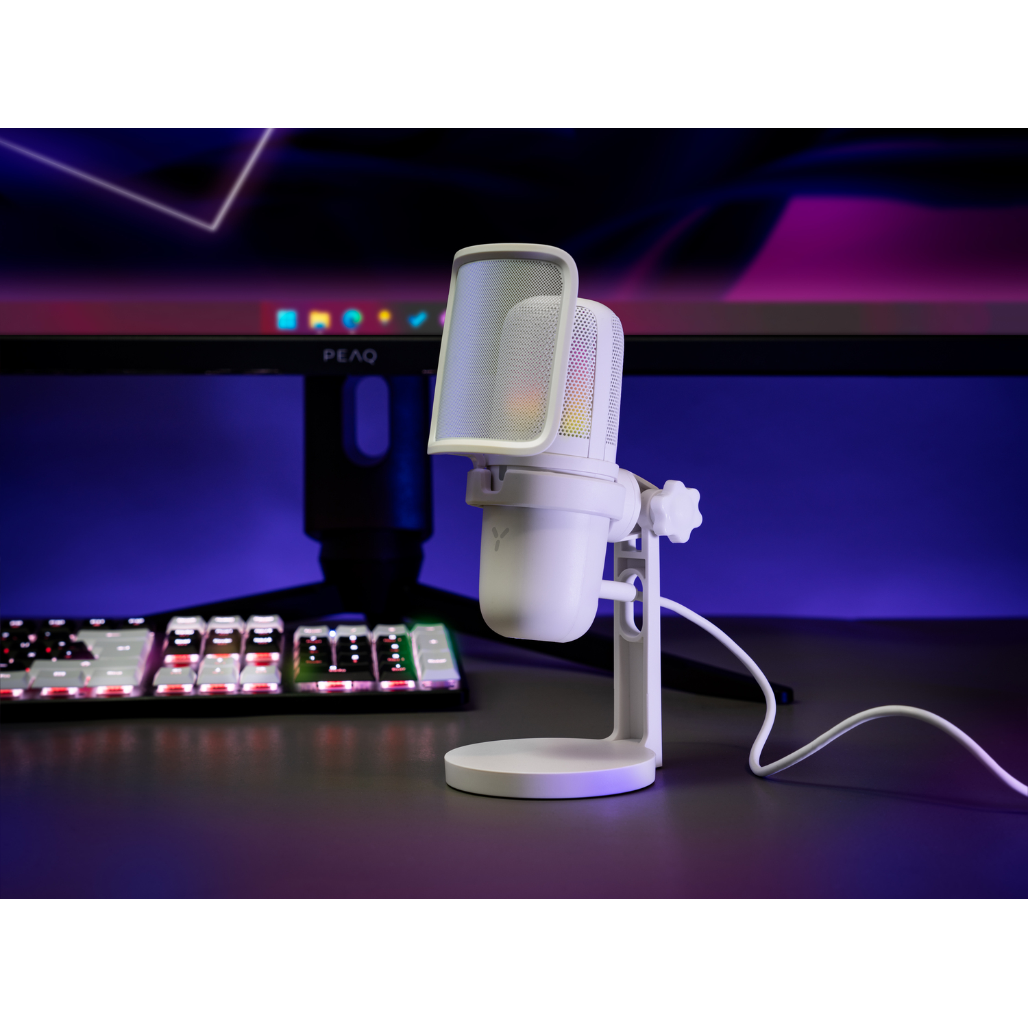 White microphone on a stand, with a keyboard and monitor in the background.