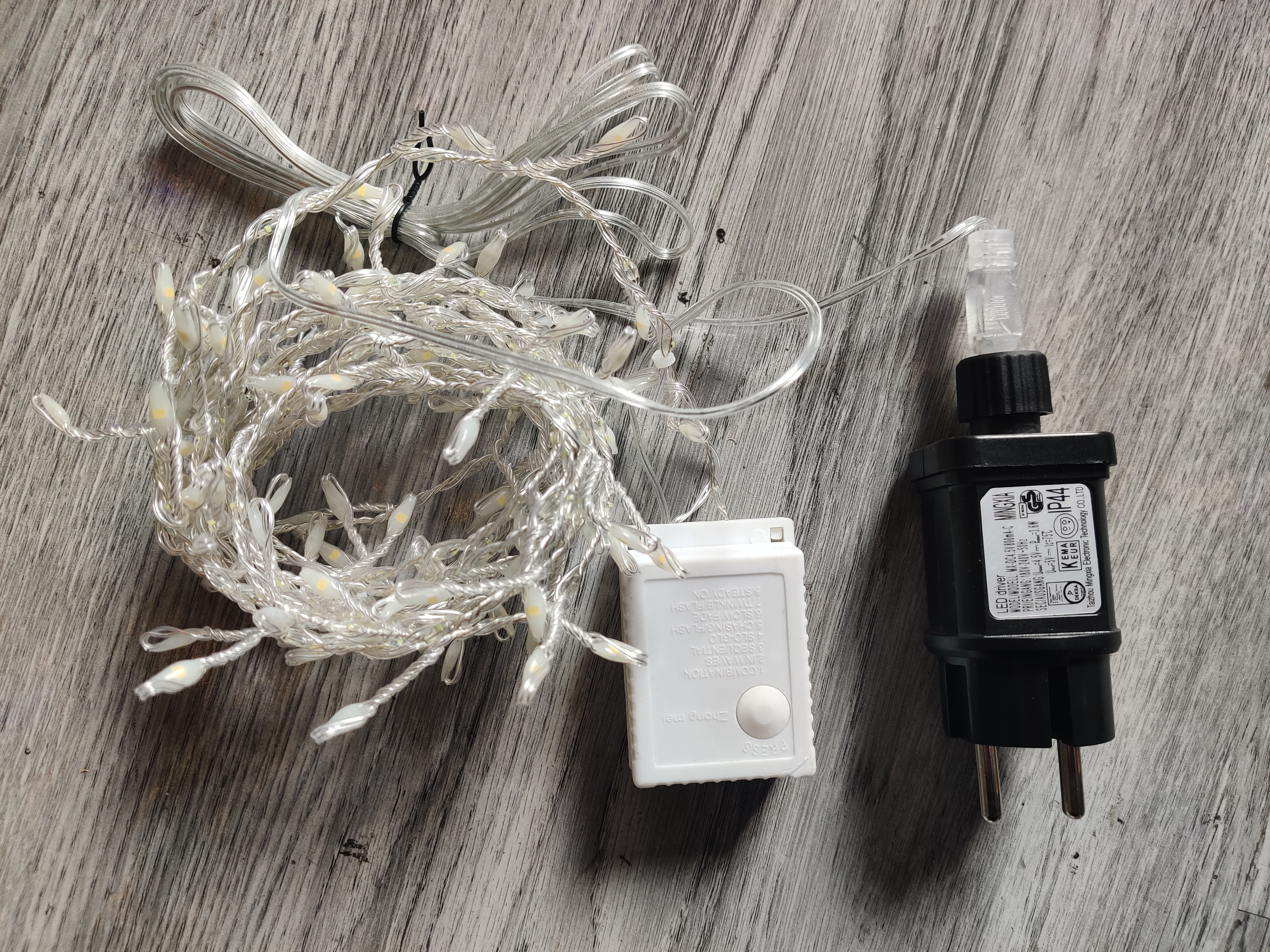 Łańcuch świetlny, adapter i jednostka sterująca na drewnie.