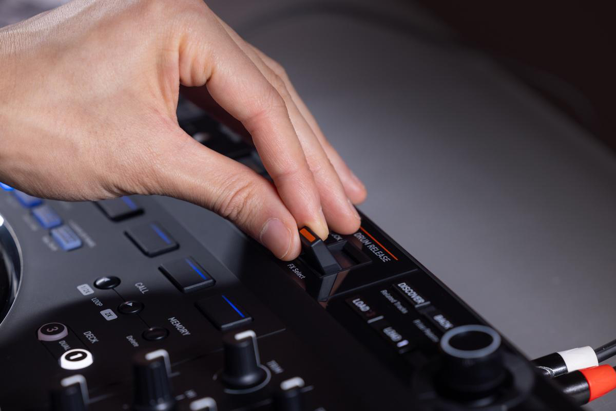 Eine Hand, die einen DJ-Mixer mit Knöpfen und Reglern einstellt, Nahaufnahme.
