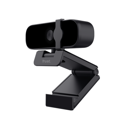 Webcam negra con soporte ajustable, frontal, fondo oscuro. Marca Trust visible.