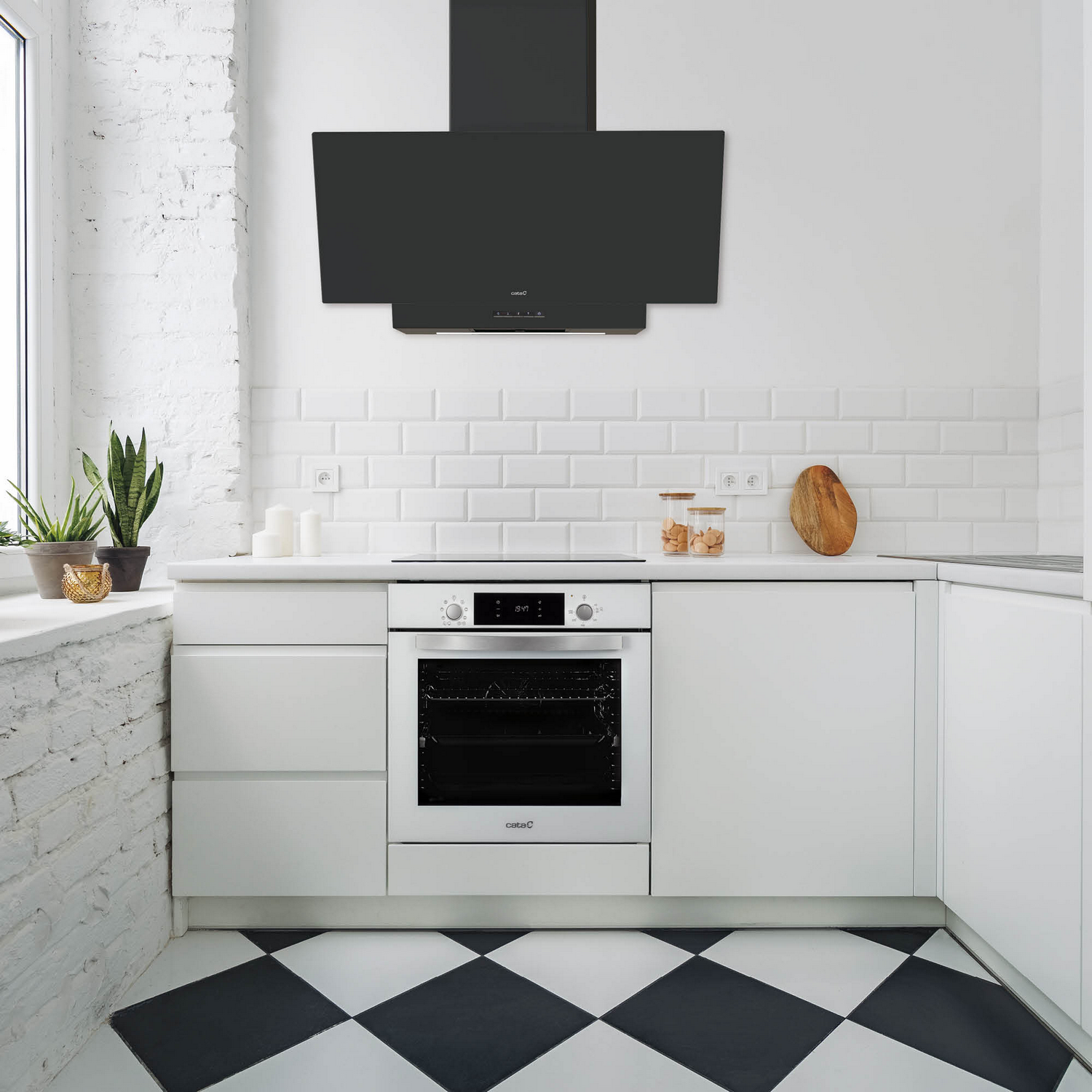 Cocina blanca con campana y horno negros. Armarios blancos, suelo de baldosas blanco y negro.
