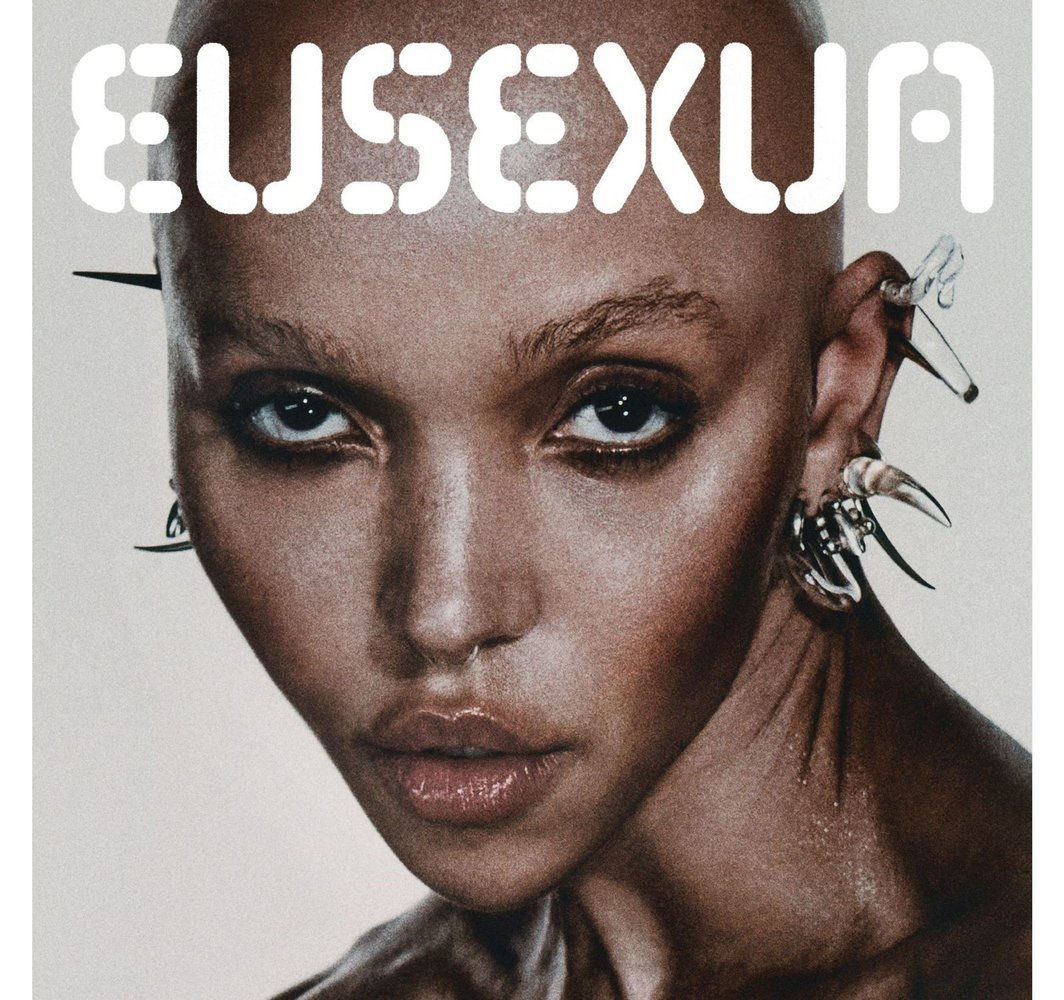 Gros plan d'une femme chauve avec des bijoux d'oreille et de visage élaborés. Texte : EUSEXUA.