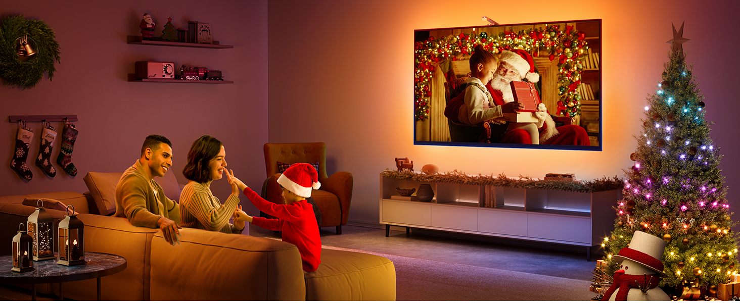 Familie schaut fern mit Weihnachtsbaum und Dekorationen. Weihnachtsmann auf dem Fernsehbildschirm.