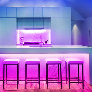 Moderne Küche mit neonlila Beleuchtung an Bar und Hockern.