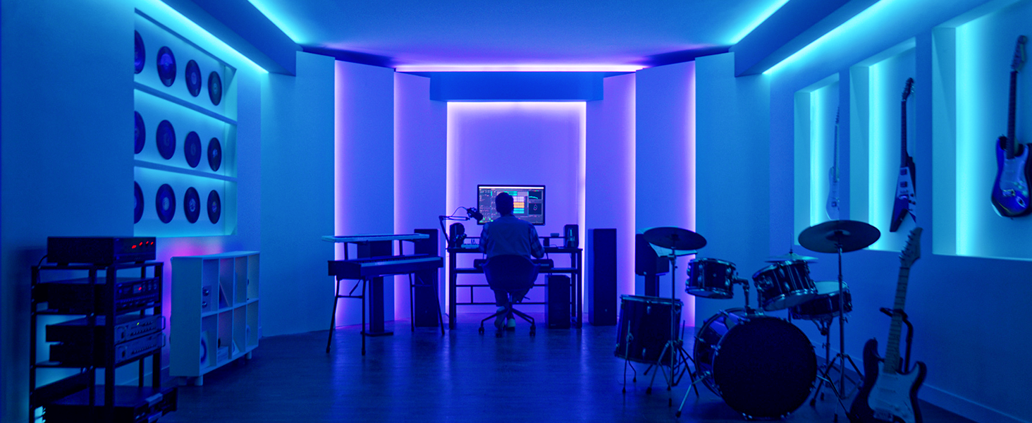 Blau beleuchtetes Musikstudio, Mann am Computer, Instrumente, Schlagzeug, Gitarren, Regale.