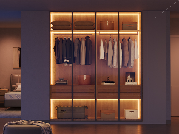 Ein gut beleuchteter Kleiderschrank mit Kleidung im Inneren. Es gibt auch Regale mit Gegenständen und Lichtern.