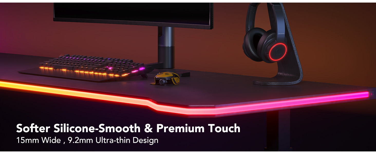 Gaming-Setup mit Schreibtisch und Tastatur, Kopfhörern und Monitor mit farbenfrohen LED-Leuchten.