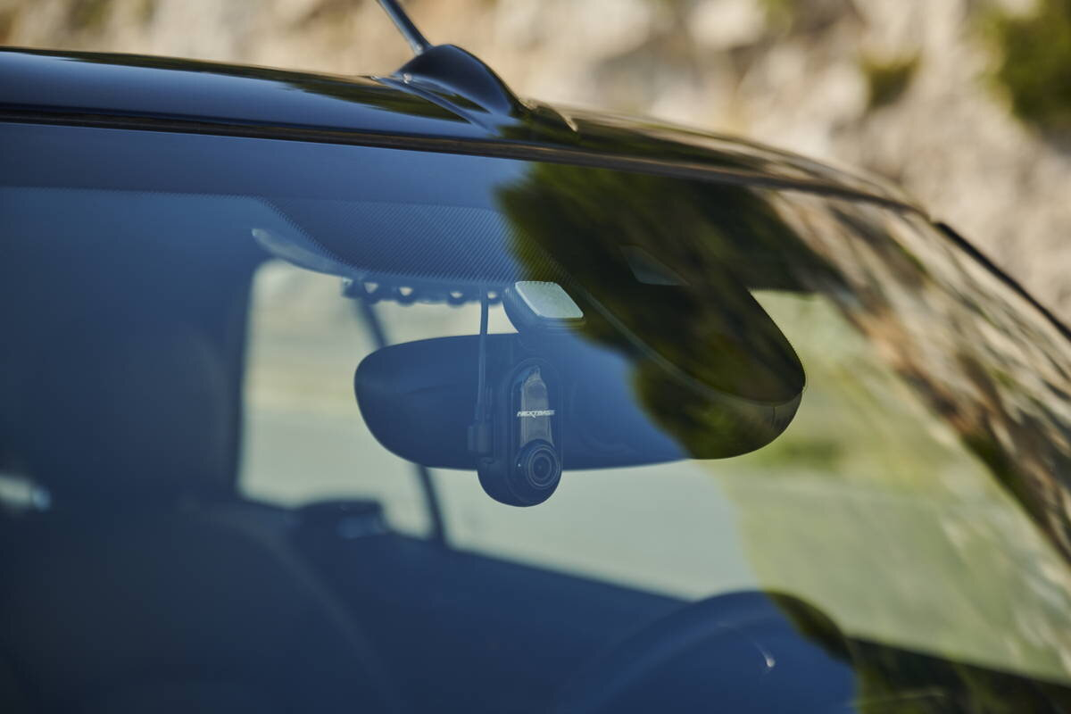 Szyba przednia samochodu z kamerą samochodową zamontowaną na lusterku wstecznym.