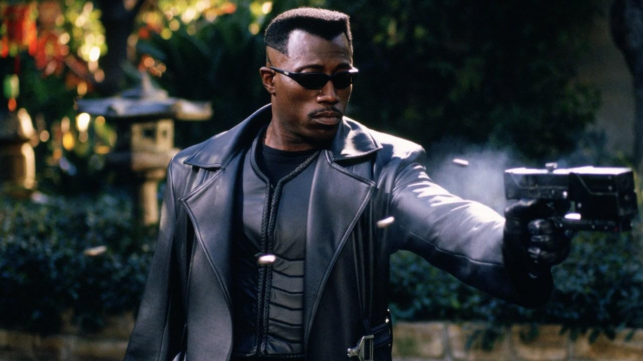 Un homme en manteau noir vise avec une arme, tirant des balles. Arrière-plan : jardin avec pagode.