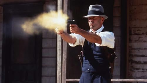 Un homme tire avec une arme à feu. De la fumée et des étincelles émanent du canon. Il porte un chapeau et un gilet.