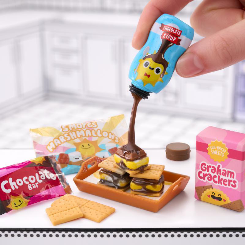 Miniatur-S'mores mit Schokoladensirup, der darüber gegossen wird, umgeben von Verpackungen.