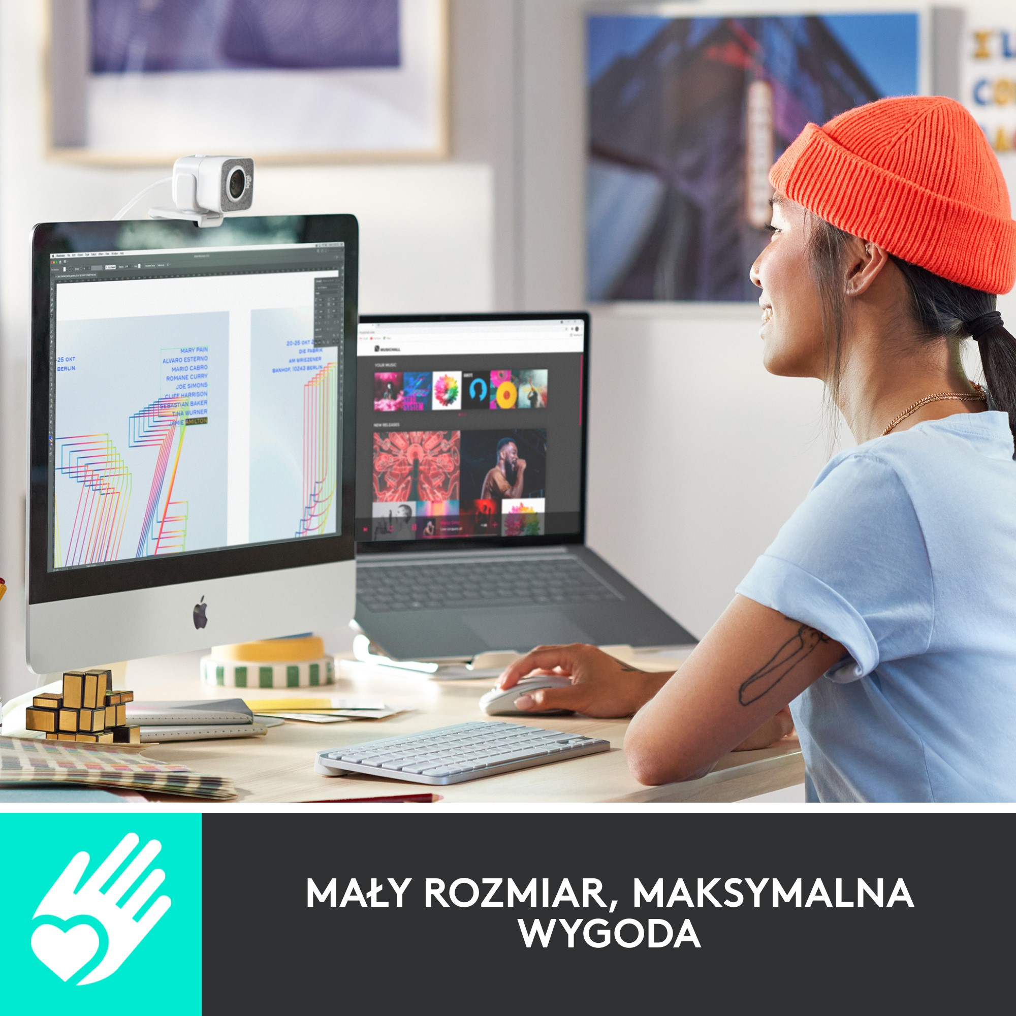 Kobieta pracująca przy biurku z komputerem, laptopem i kamerą internetową.