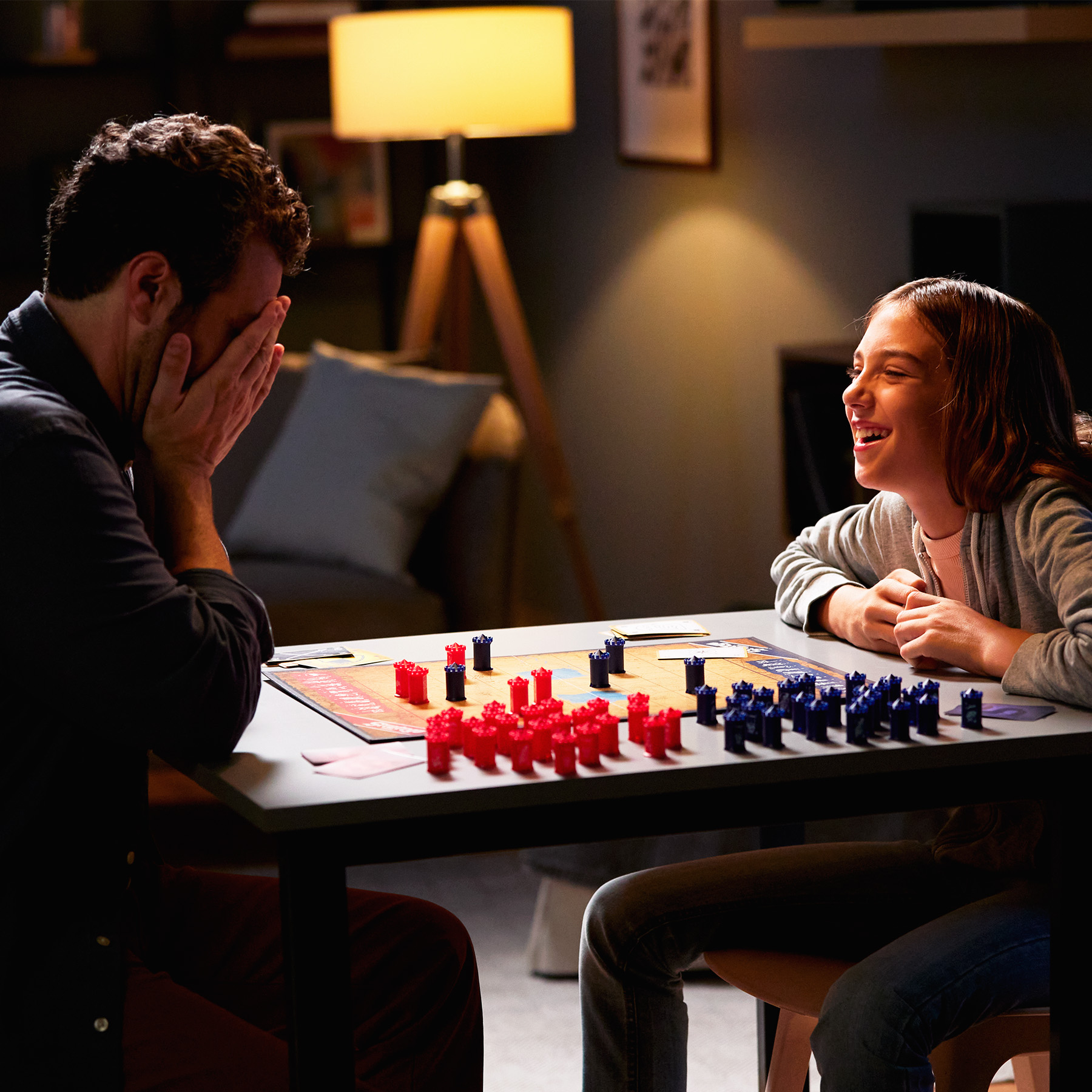 Een vader en dochter spelen een bordspel. De dochter lacht.