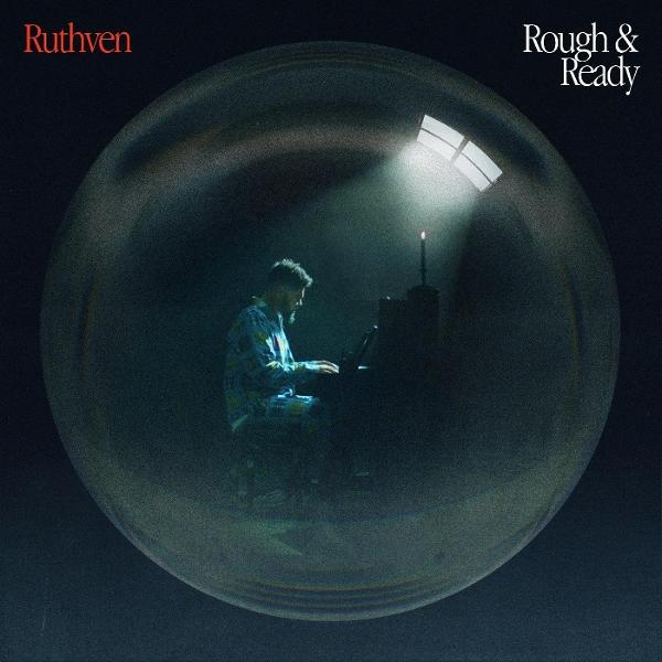 Albumcover: Mann spielt Klavier in einer Blase, Scheinwerfer, dunkle Umgebung.