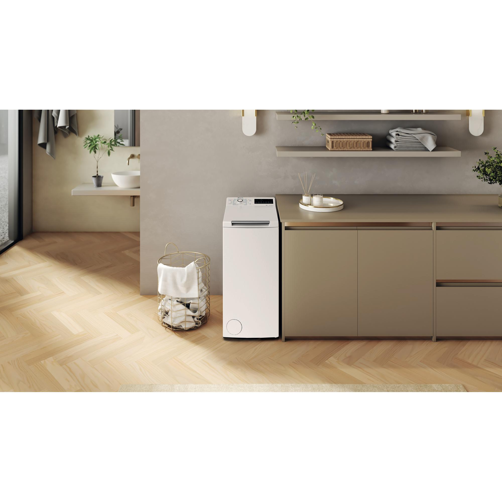 Eine weiße Waschmaschine und ein goldener Wäschekorb mit weißer Kleidung.