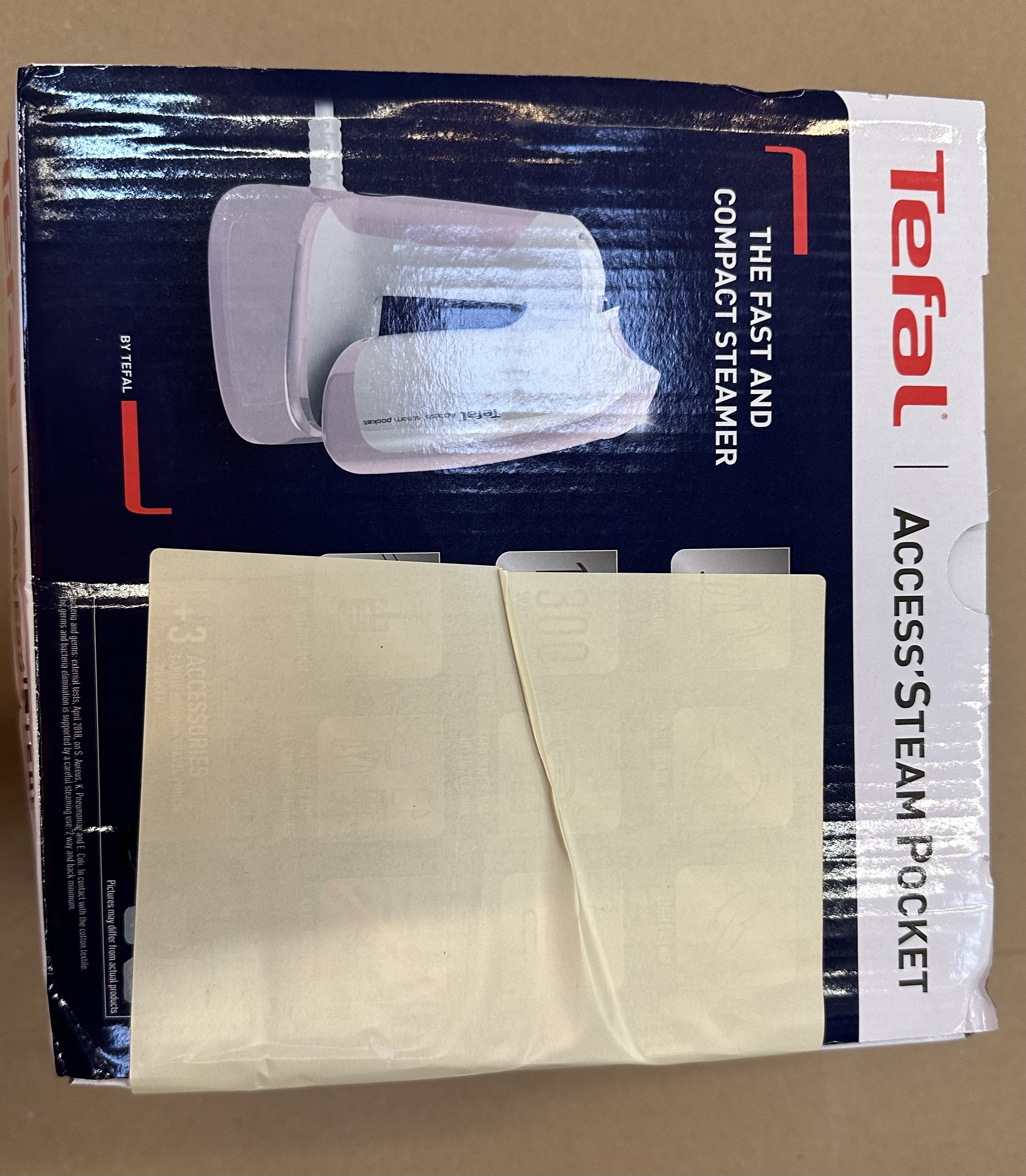 Pudełko parowaru Tefal. Produkt jest w pudełku. Biały papier jest przymocowany do pudełka.