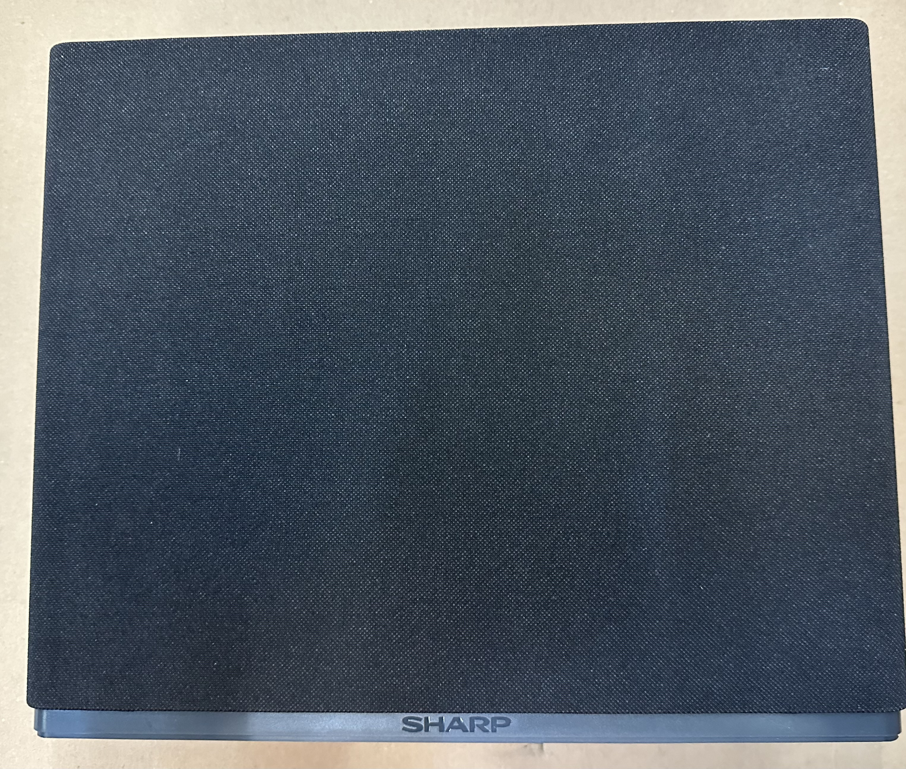 Czarny głośnik z czarnym materiałowym przodem i logo SHARP.