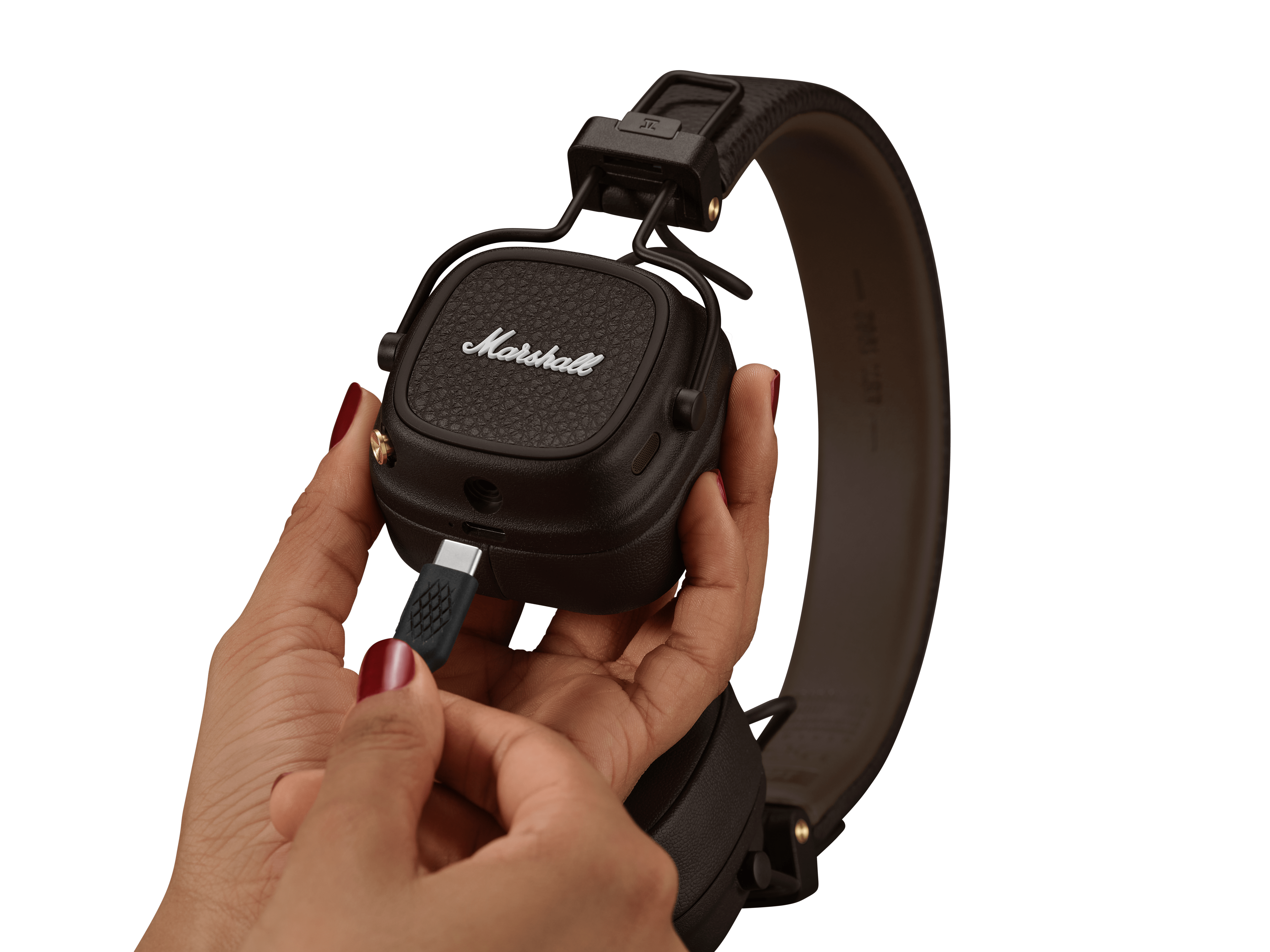 Bir kişi, koyu kahverengi bir Marshall kulaklığına USB-C kablosu takıyor.