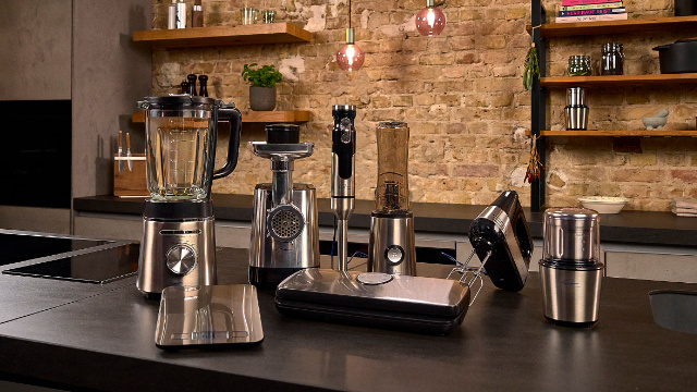 Eine Küchenarbeitsplatte mit verschiedenen silbernen und schwarzen Küchengeräten. Enthält einen Mixer und eine Waage.