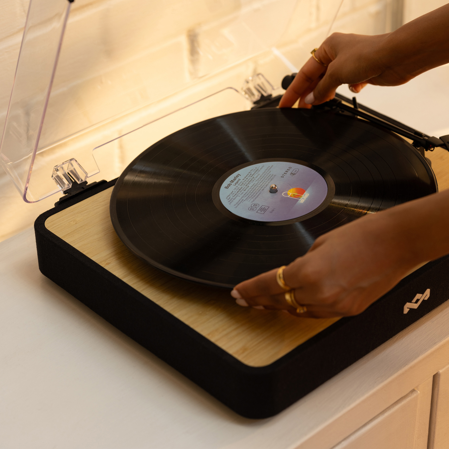 Person's hands placing a vinyl record on a turntable.