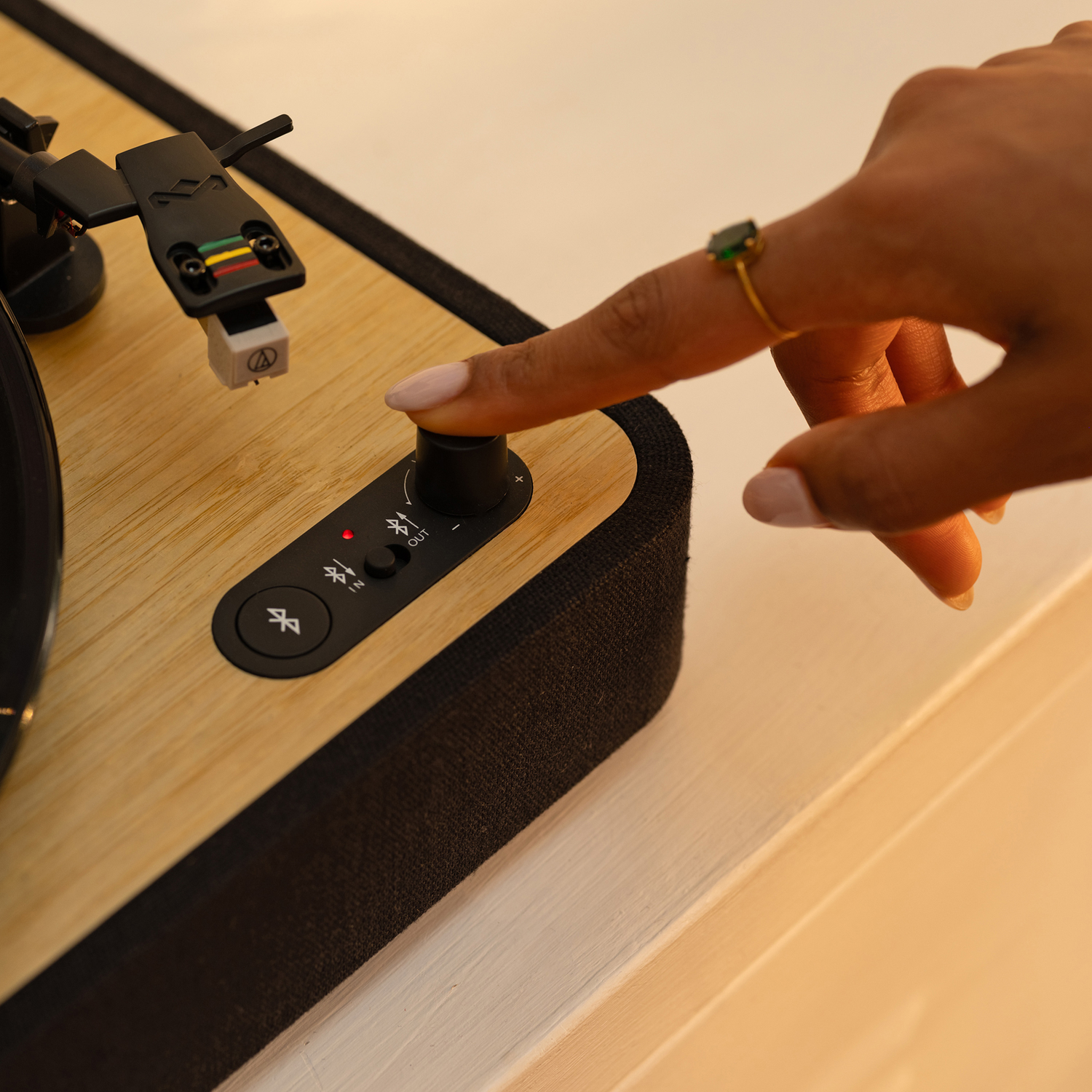 Close-up of turntable controls. A hand is adjusting a control knob. Wooden surface.