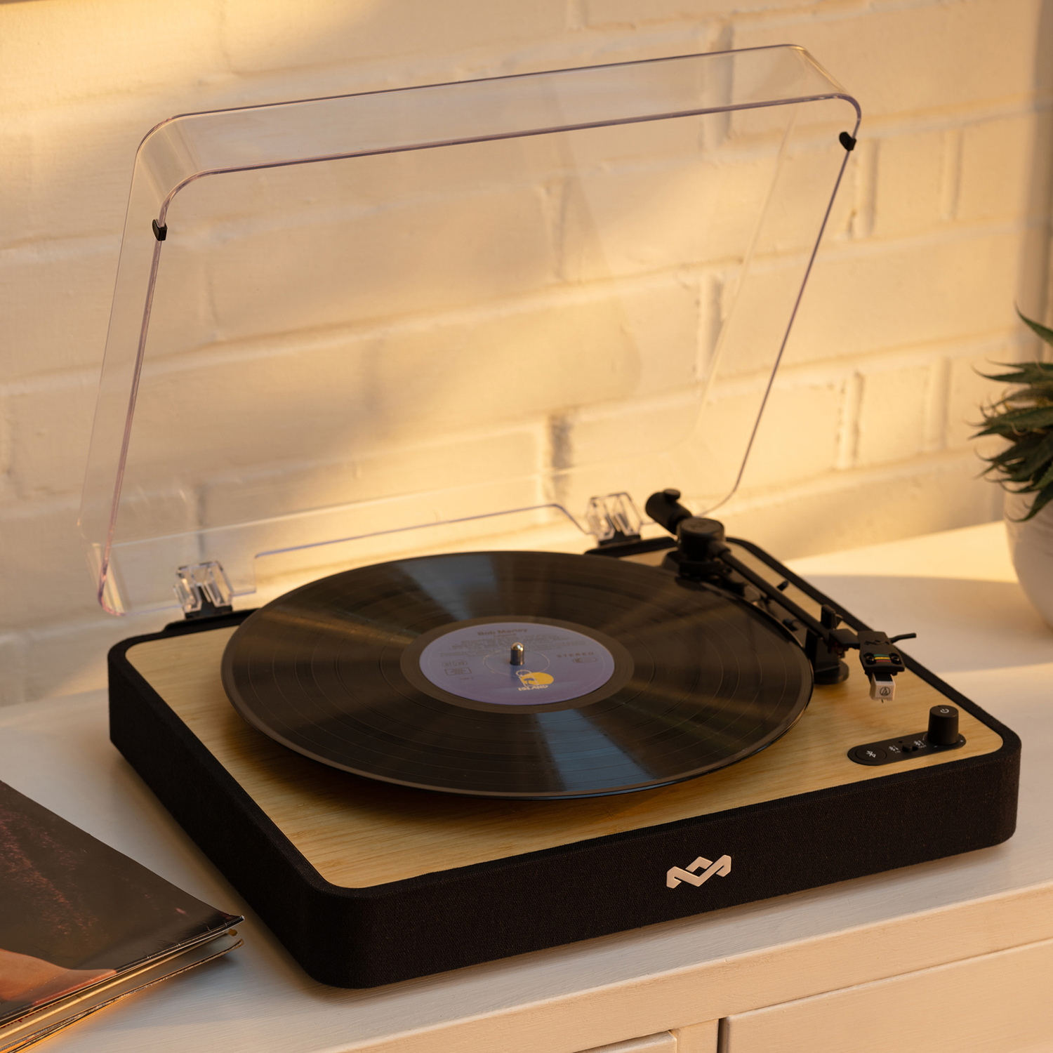 A record player with a vinyl record, set on a wooden table with a plant.