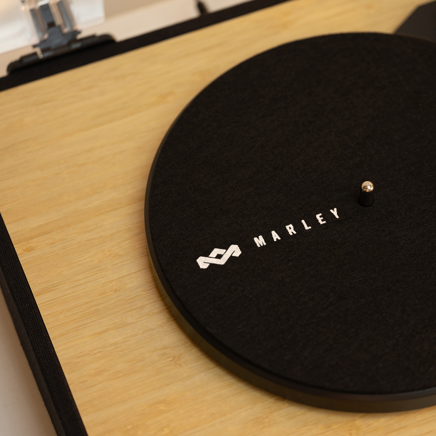 Black turntable with the Marley logo and a silver stylus on a wooden surface.