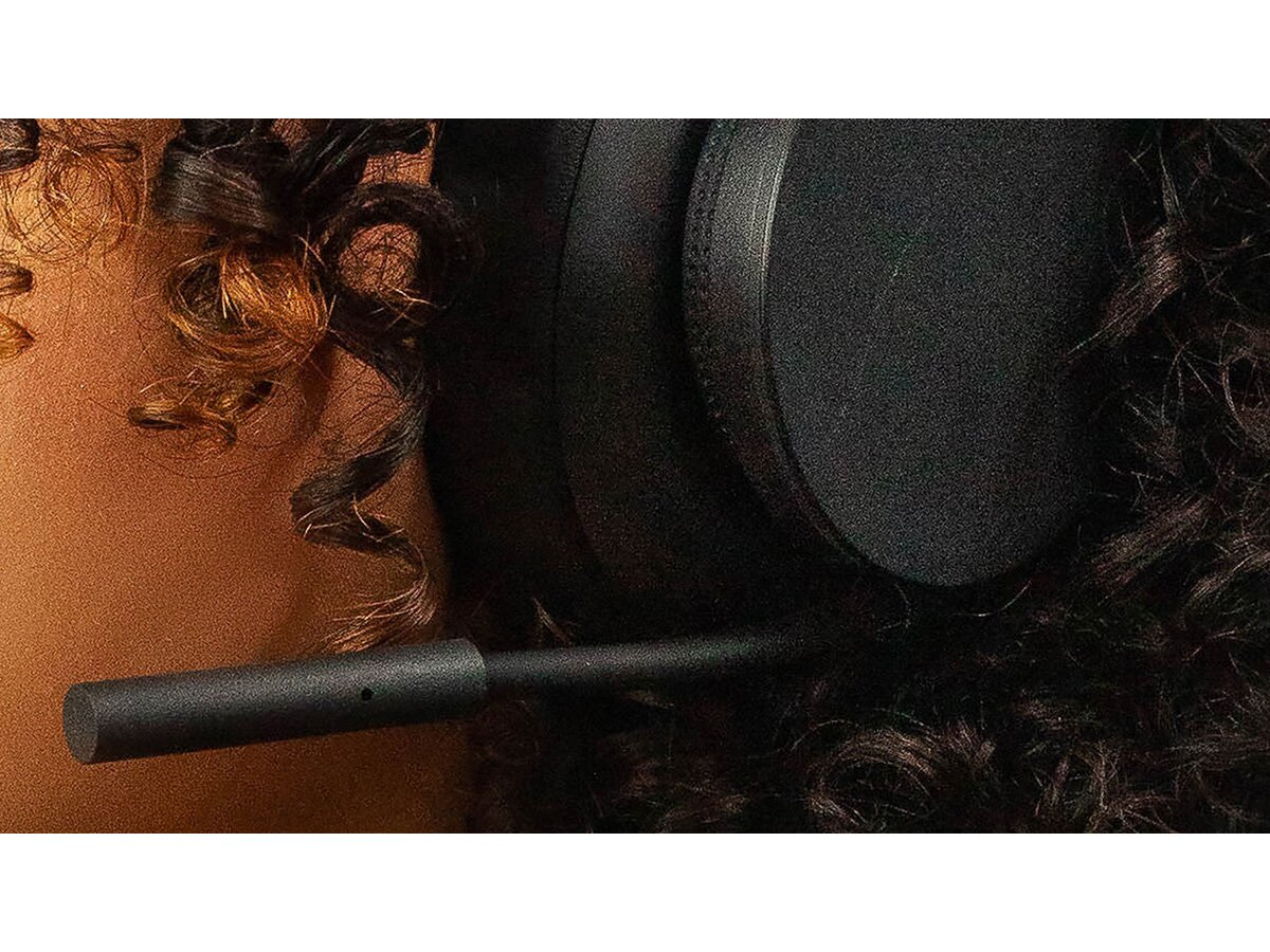 Czarny zestaw słuchawkowy z mikrofonem, część przylega do kręconych włosów.