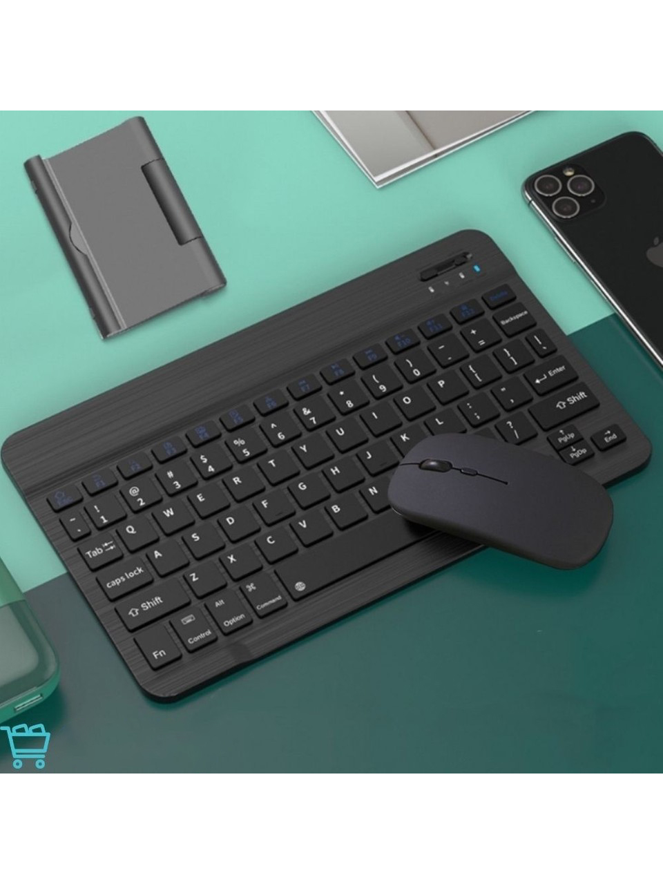 Siyah klavye ve fare seti, yeşil ve mavi bir yüzeyde. Bir telefon ve stand da mevcut.