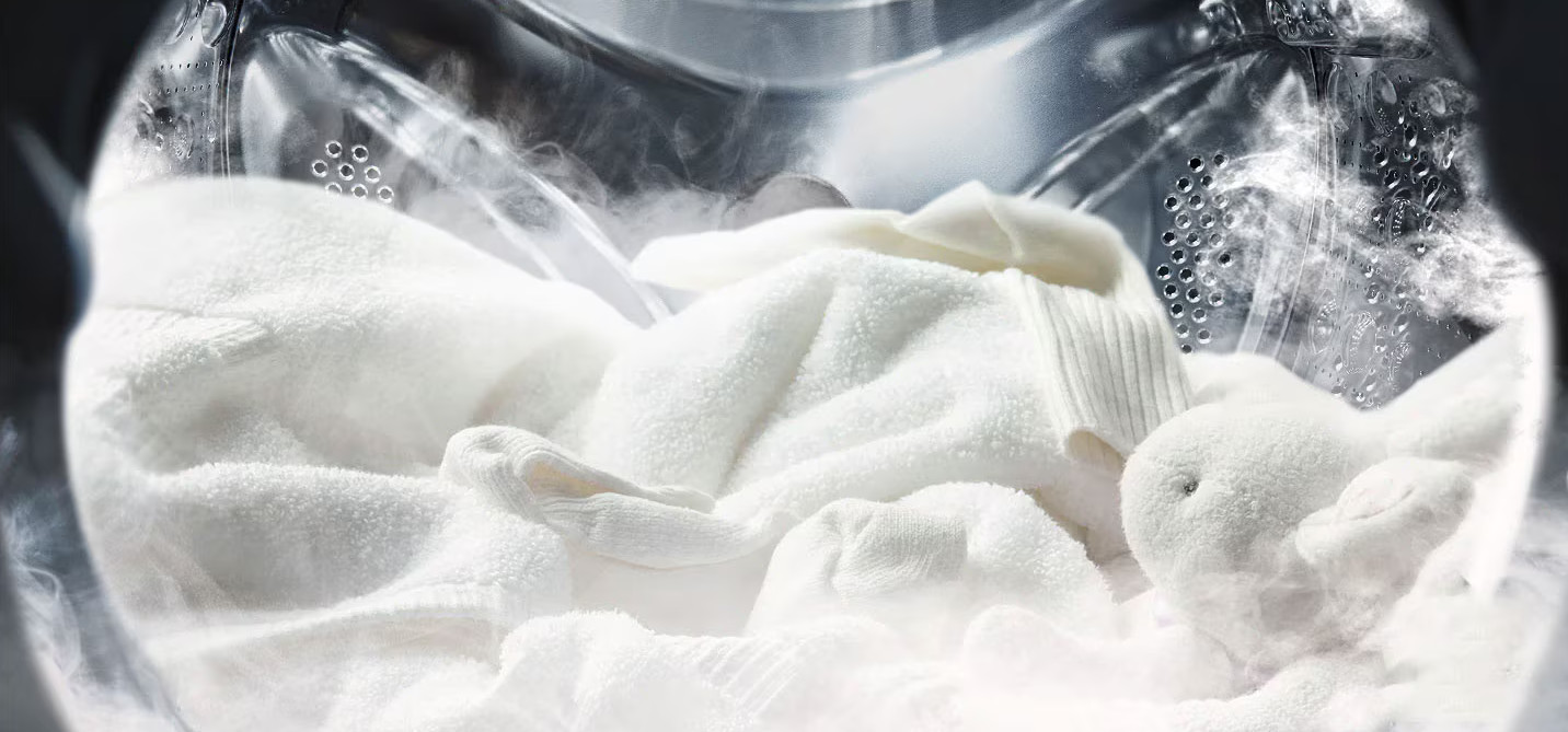 Białe ręczniki parujące w pralce.