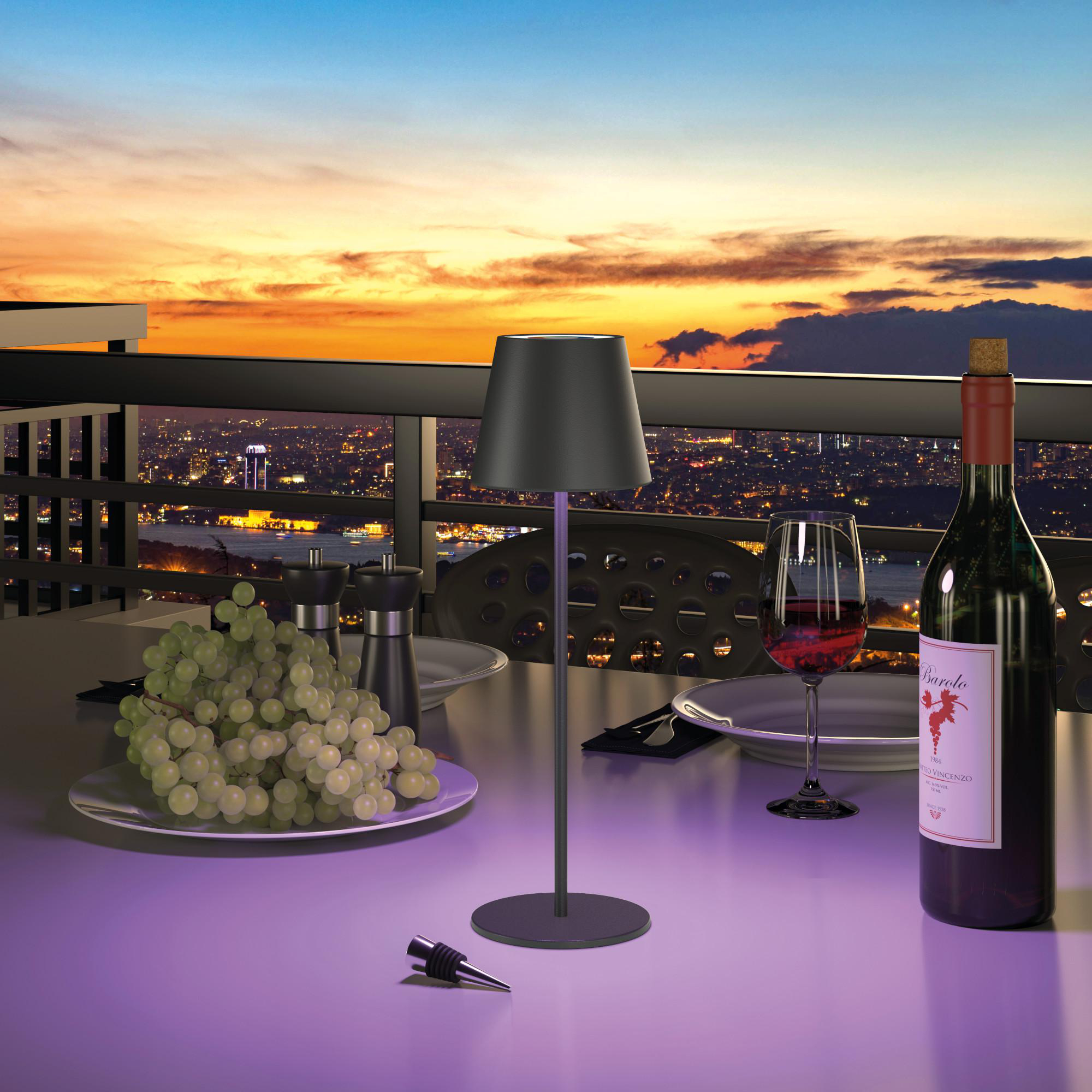 Ein Tisch für ein Abendessen auf einem Balkon bei Sonnenuntergang mit einer Weinflasche.