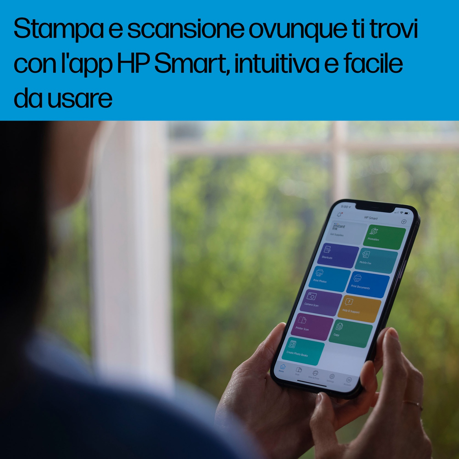 La mano di una persona che tiene un telefono che mostra l'interfaccia dell'app HP Smart, con una finestra sullo sfondo.