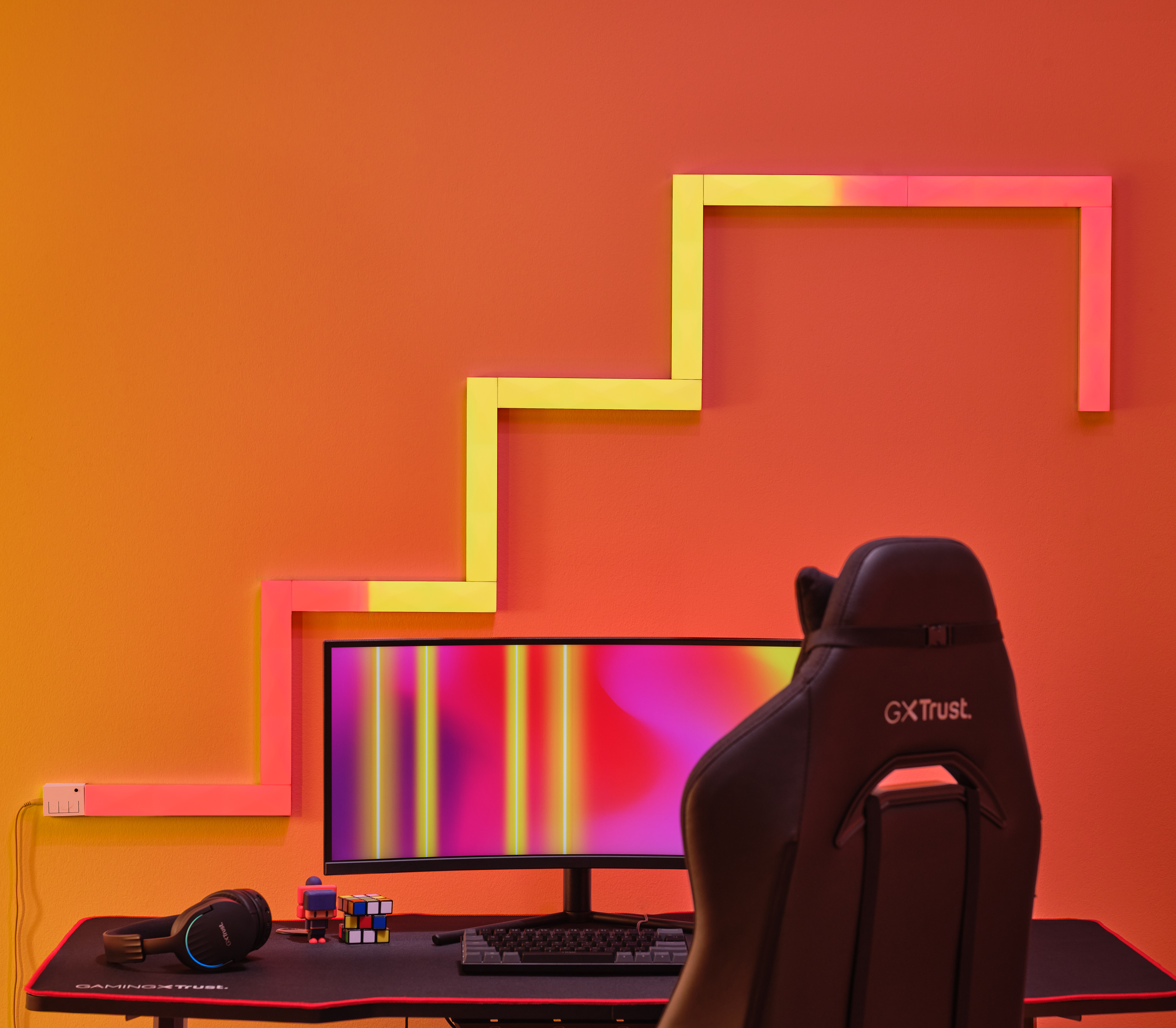 Gaming-Setup mit Neonlicht-Design an der Wand und einem Schreibtisch.