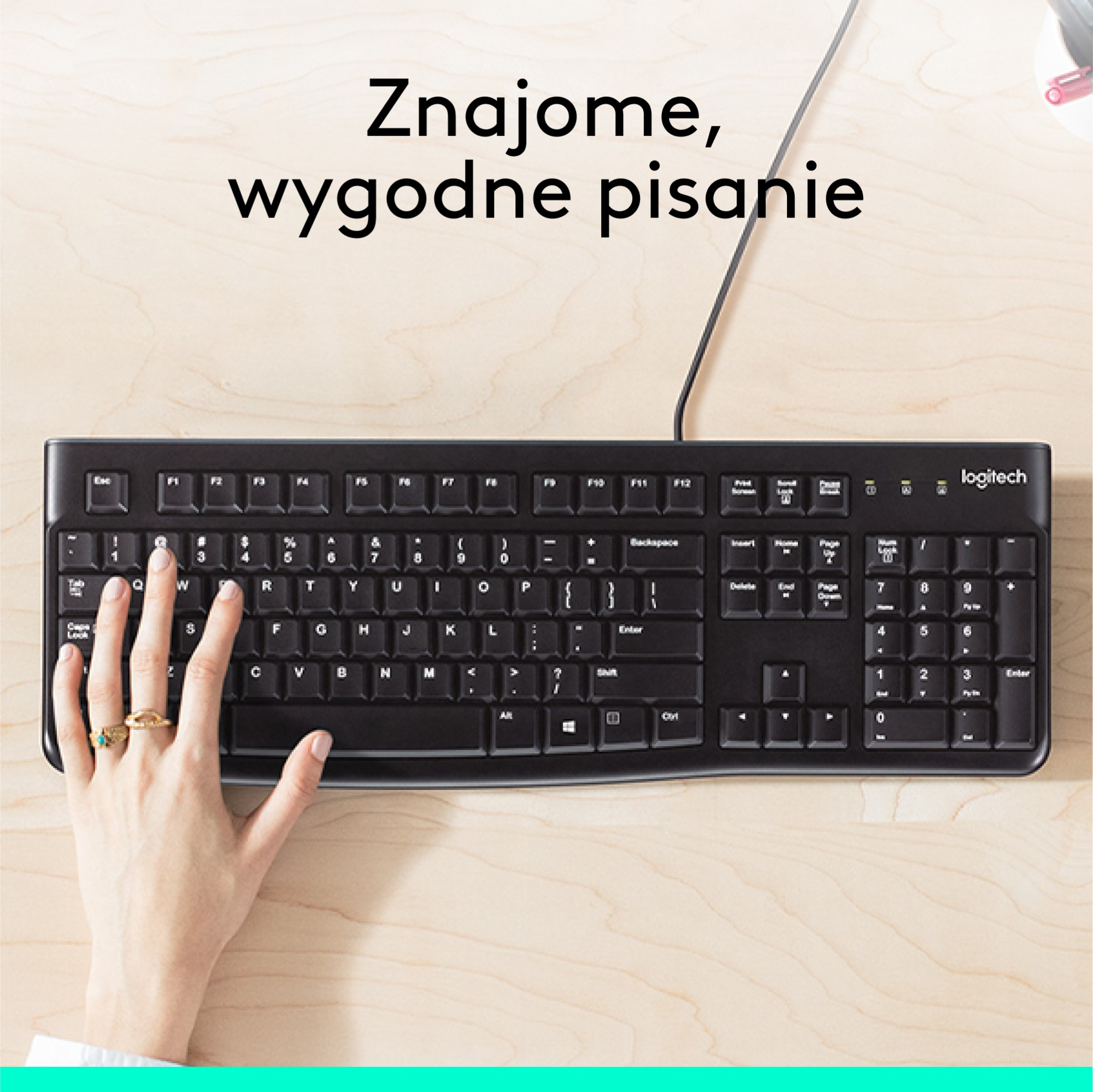 Widok z góry na czarną klawiaturę, z ręką spoczywającą na niej. Tekst powyżej mówi: 'znajome, wygodne pisanie'.