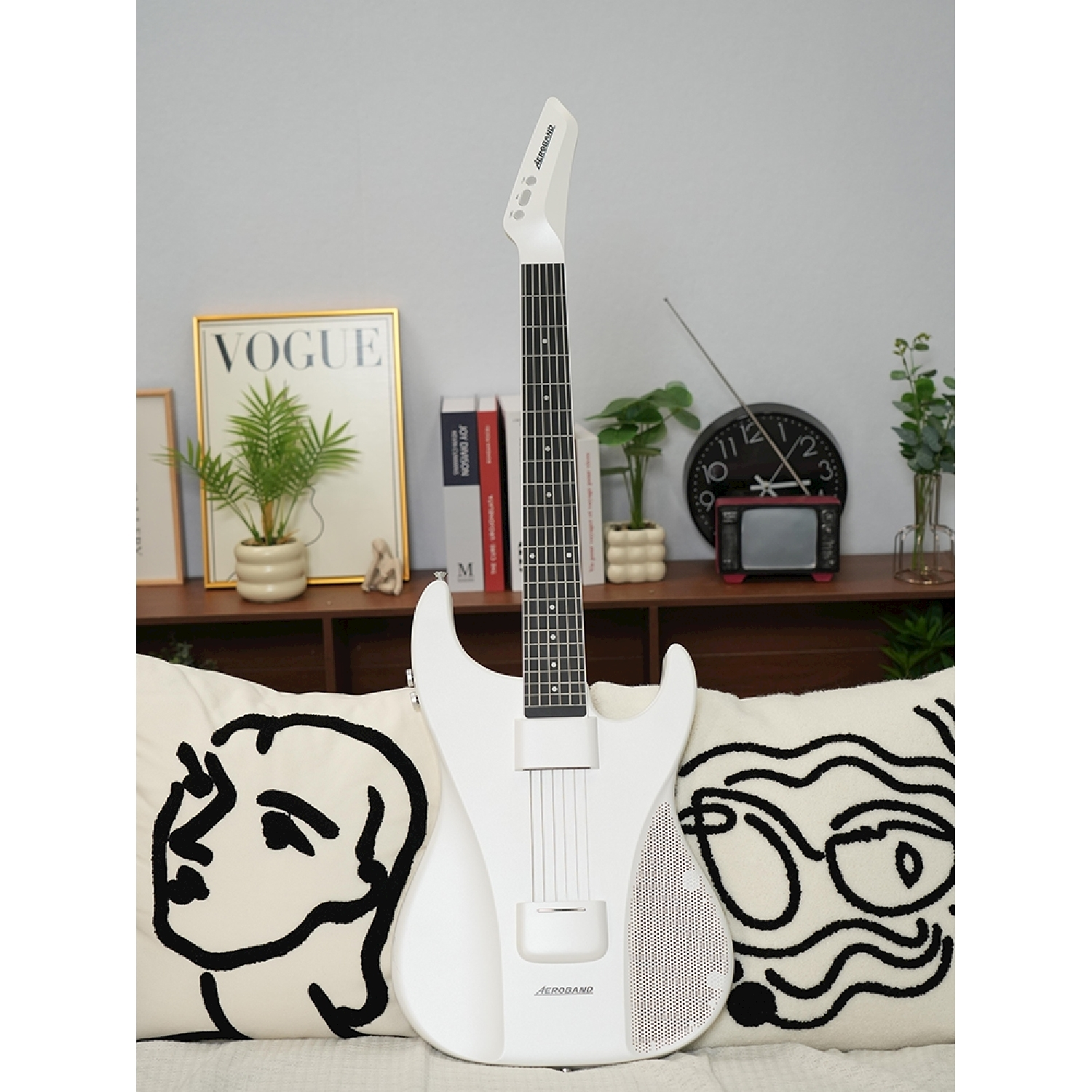 Chitarra elettrica bianca su un divano con un poster VOGUE e piante.