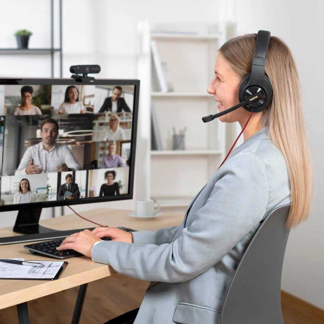 Mujer en videollamada con auriculares y monitor.