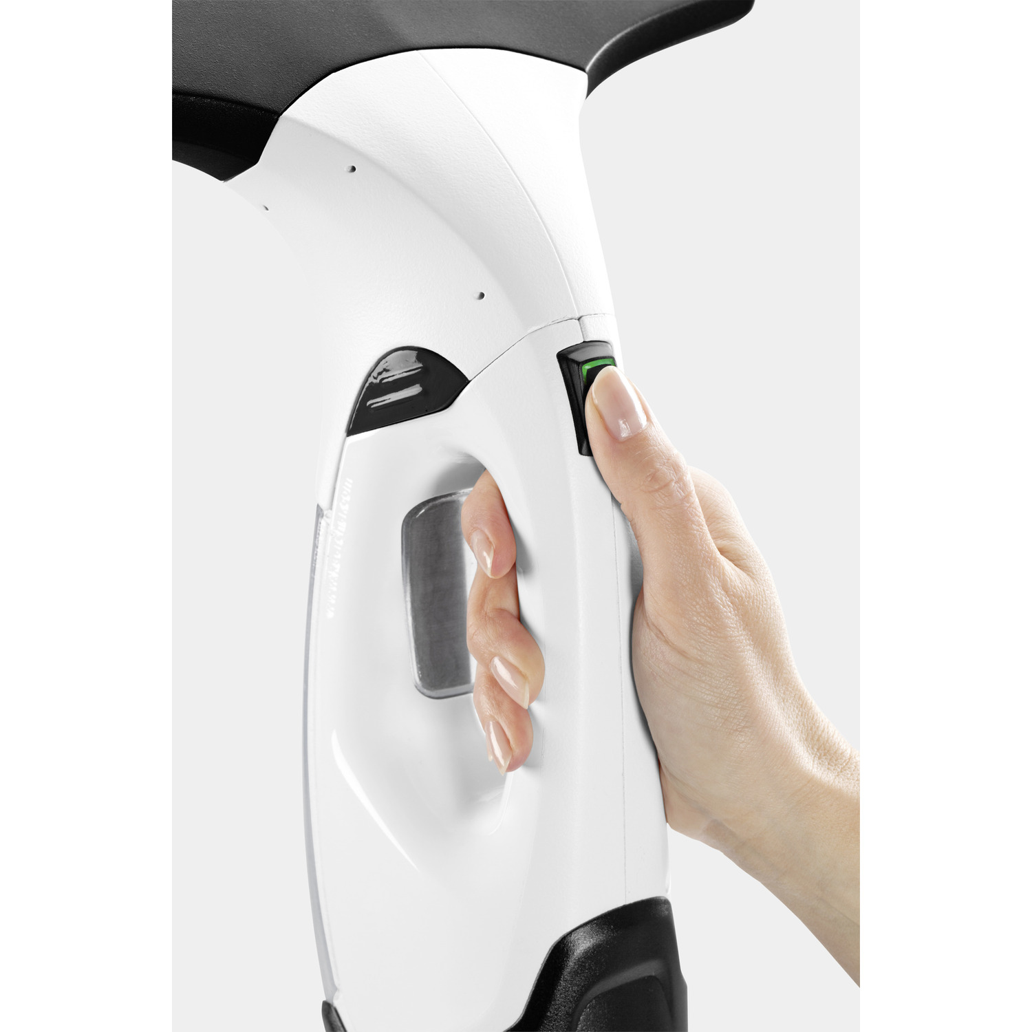 A hand presses a green button on a white and black window cleaner.