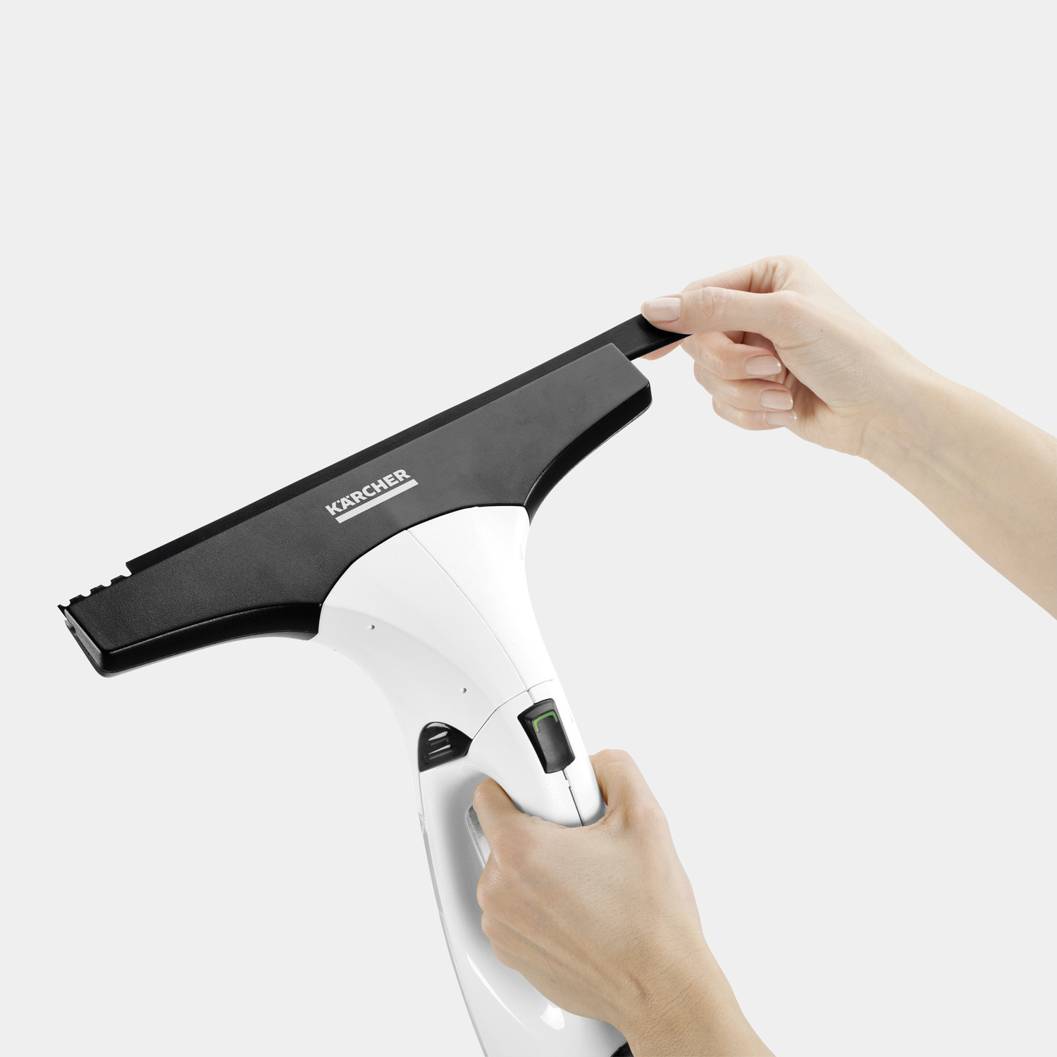 A person's hands holding a white and black window cleaner. One hand touches the black wiper blade.