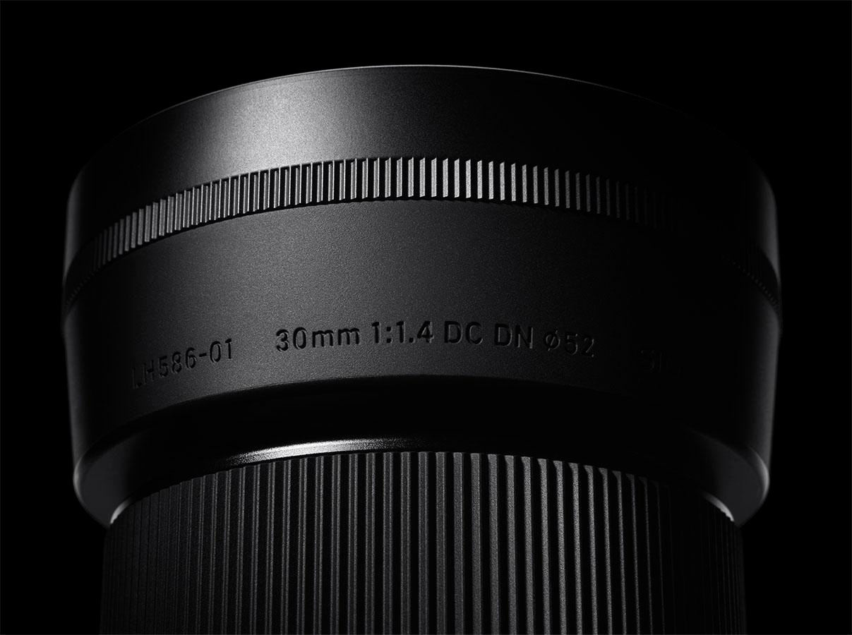 Schwarzes Kameraobjektiv, Text mit der Aufschrift '30mm 1:1.4 DC DN ø52' ist sichtbar.