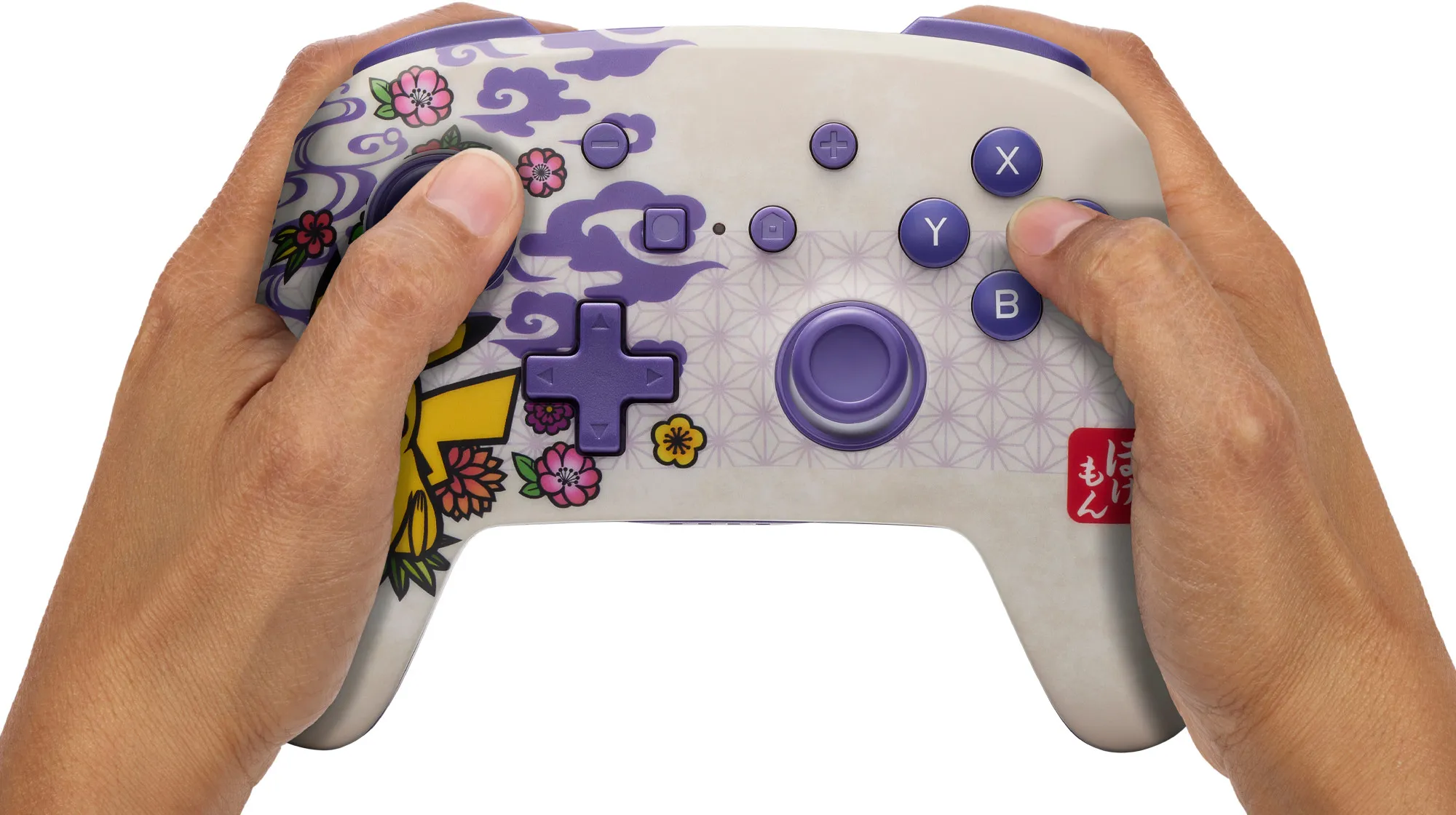 Hände halten einen weißen Gamecontroller mit lila Knöpfen und floralem Design. Der Hintergrund ist weiß.