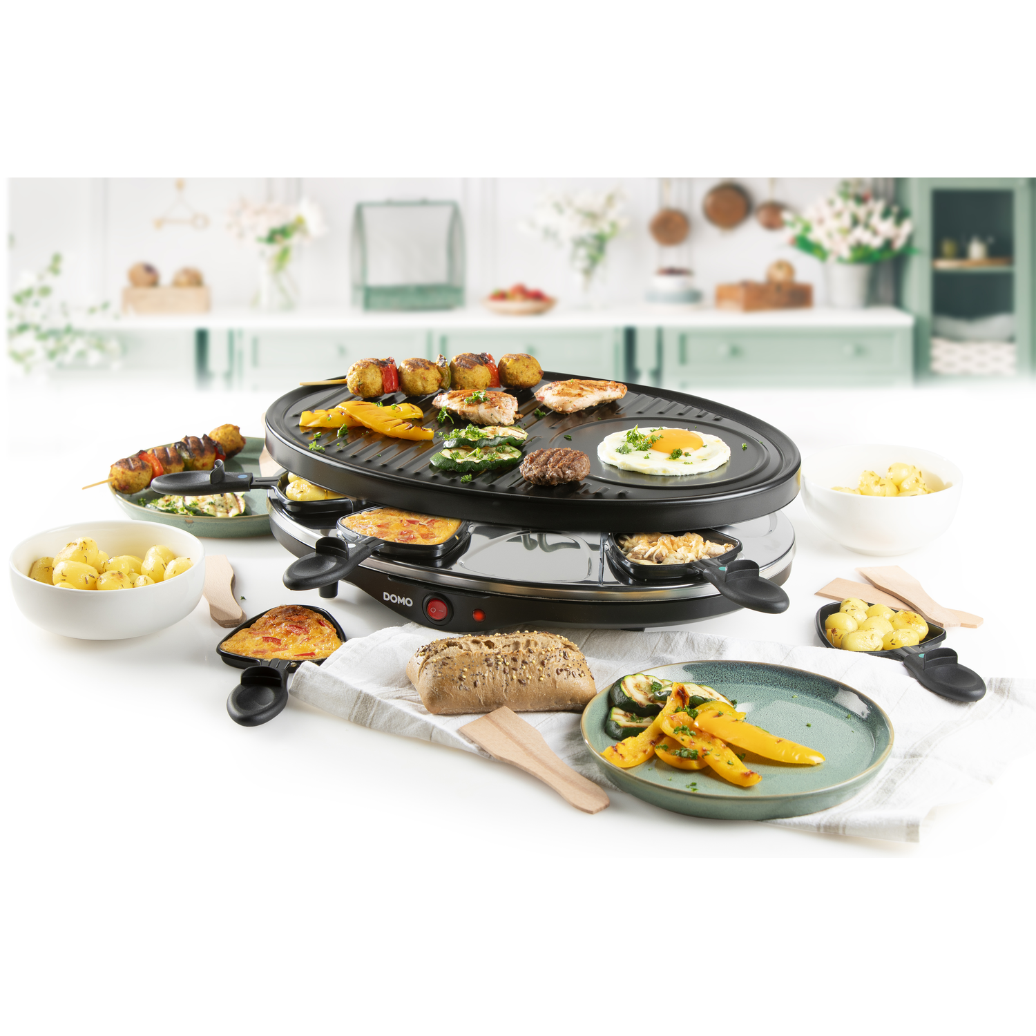 Raclette grill with various cooked foods. The scene has plates, bowls, and wooden spatulas. White background.