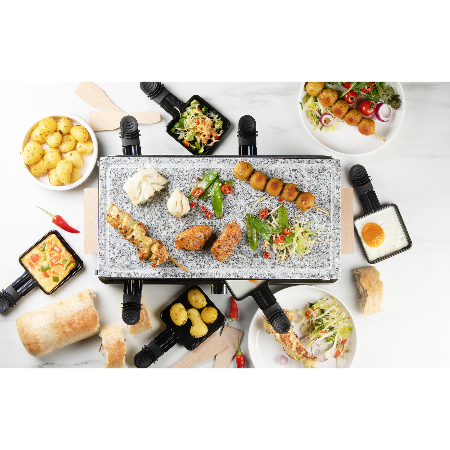 Racletteset met eten op een wit oppervlak.