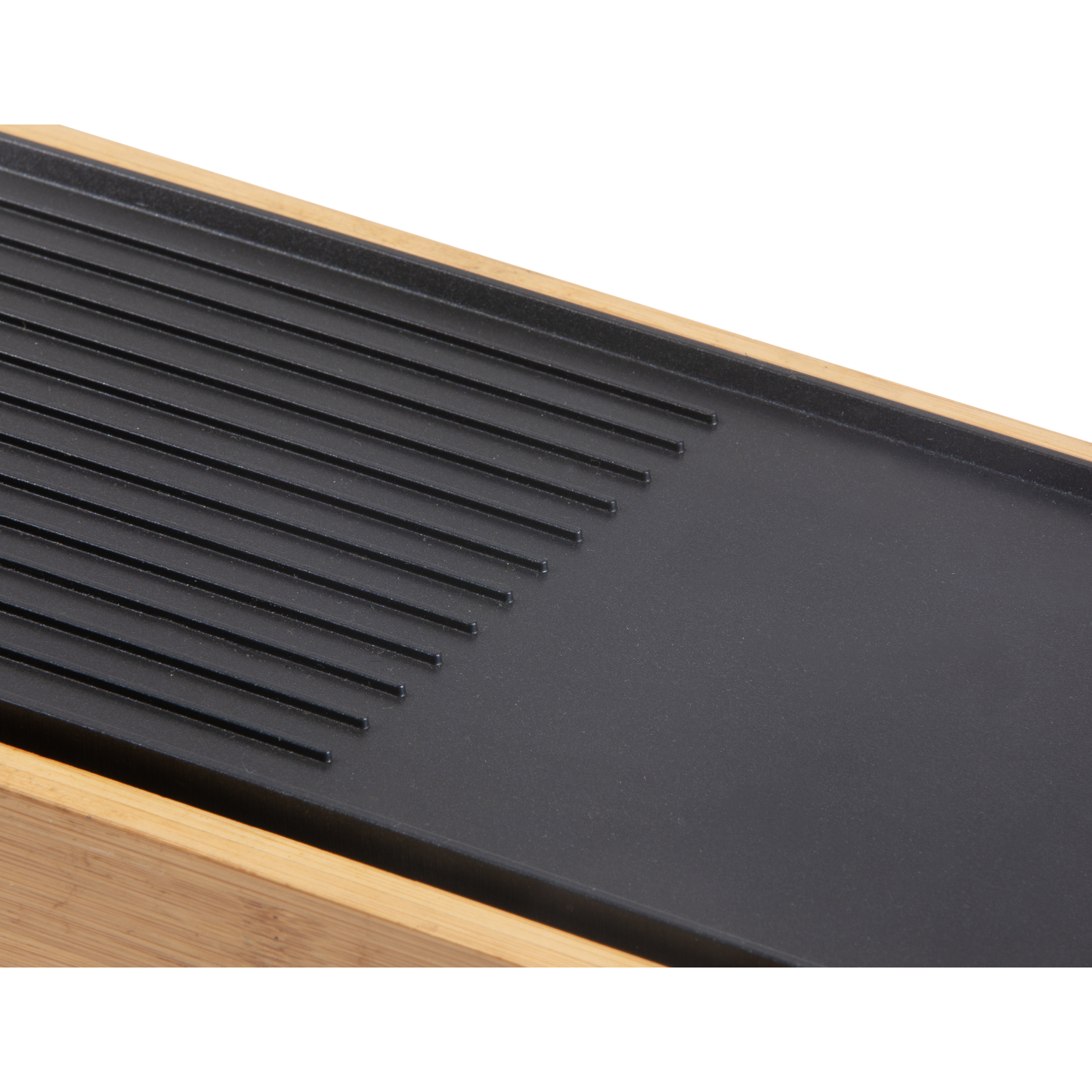 Close-up of a black grill top with grill lines on the left and a flat surface.