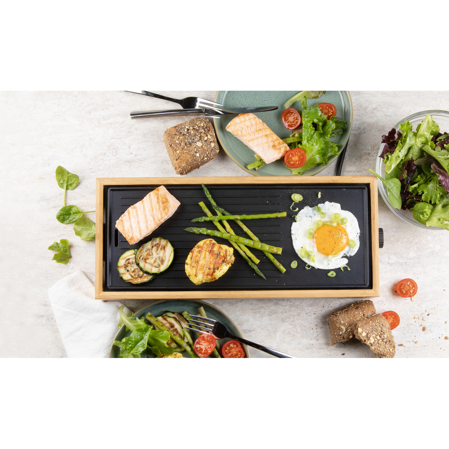A griddle with food on it, including salmon and an egg, with plates.