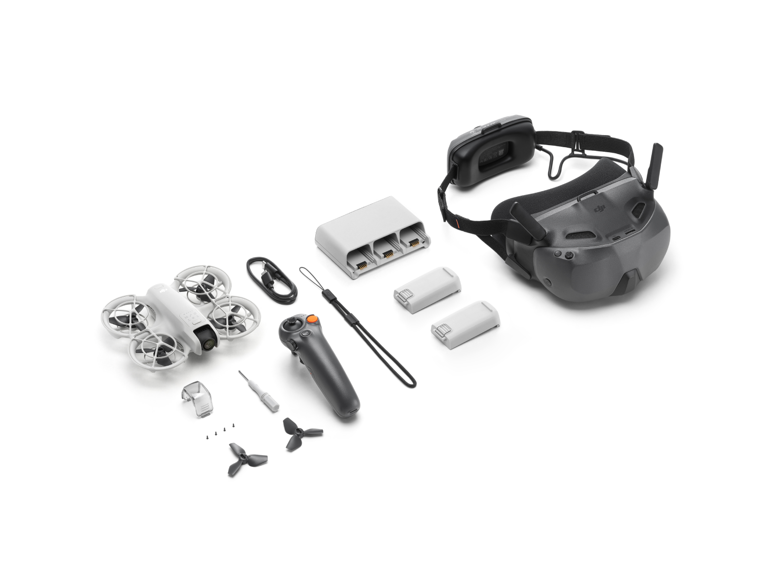 Kit de drones con dron, controlador, baterías, auriculares y accesorios sobre blanco.