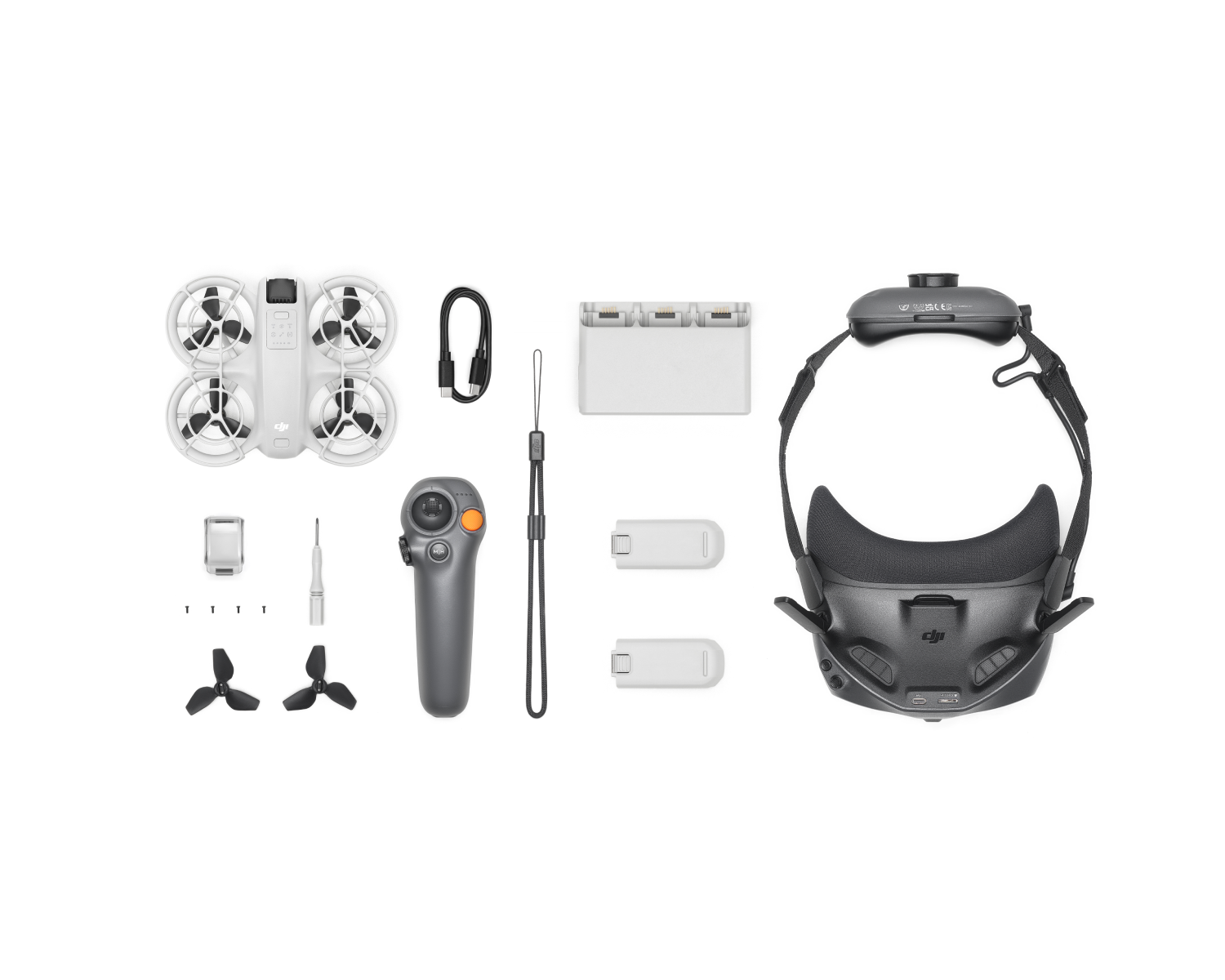 Kit de drones con dron, controlador, baterías, auriculares y accesorios sobre blanco.