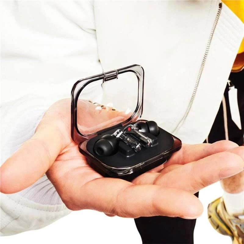 Persona sostiene auriculares transparentes con estuche de carga en las manos.