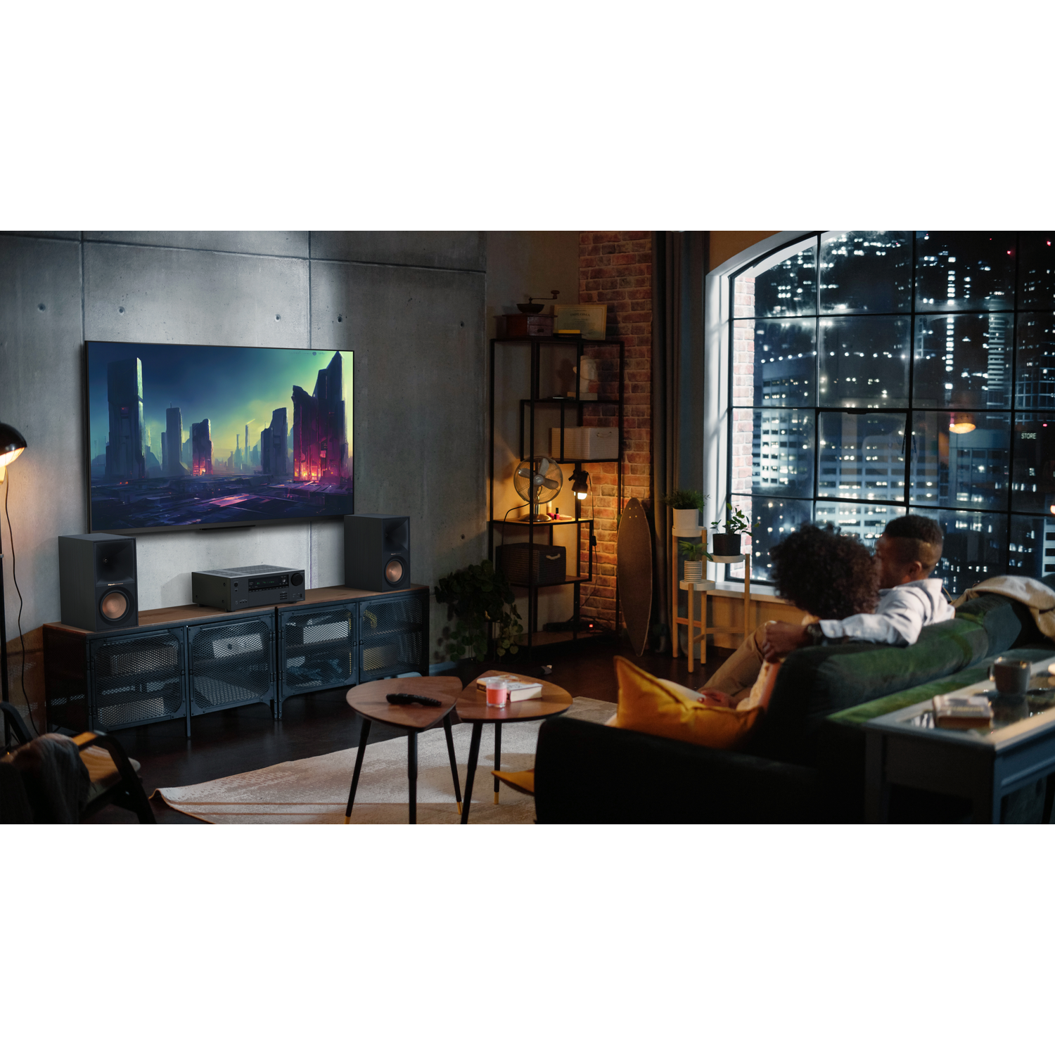 A living room with a couple watching a TV. Speakers sit on a cabinet.